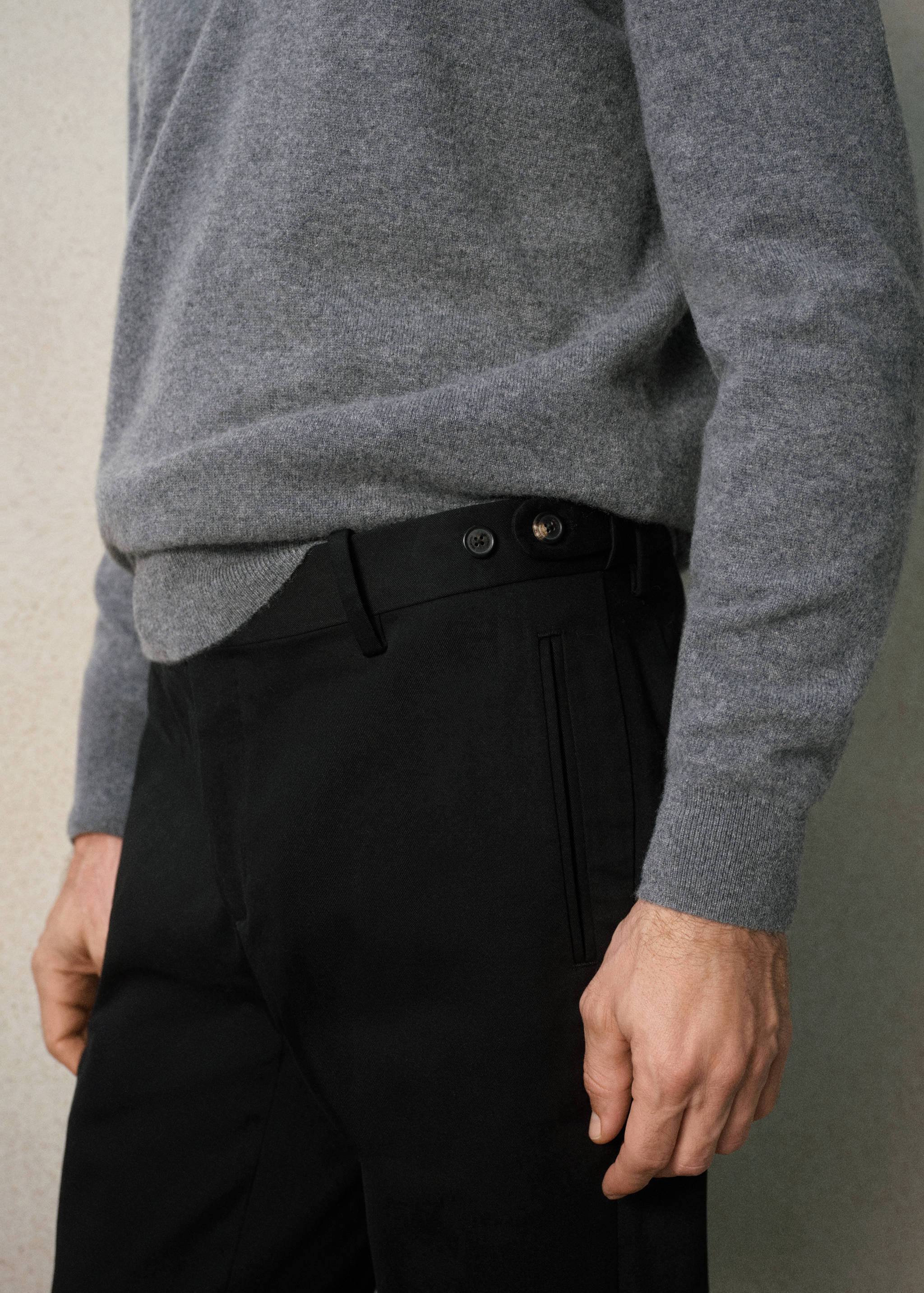 Black trousers with a side button adjustment tab on the waistband.