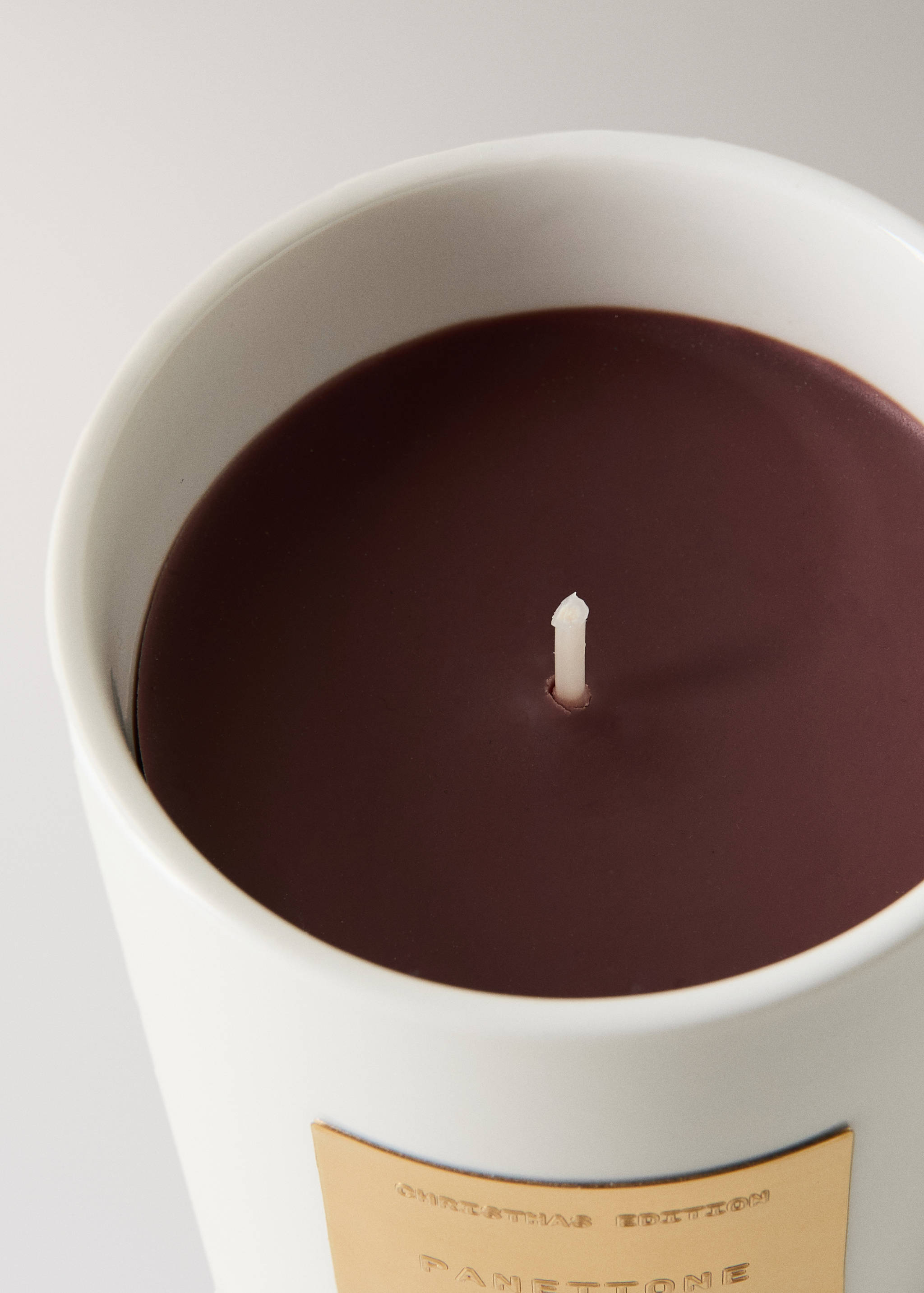 Close-up of a scented candle in a white ceramic holder with dark burgundy wax.