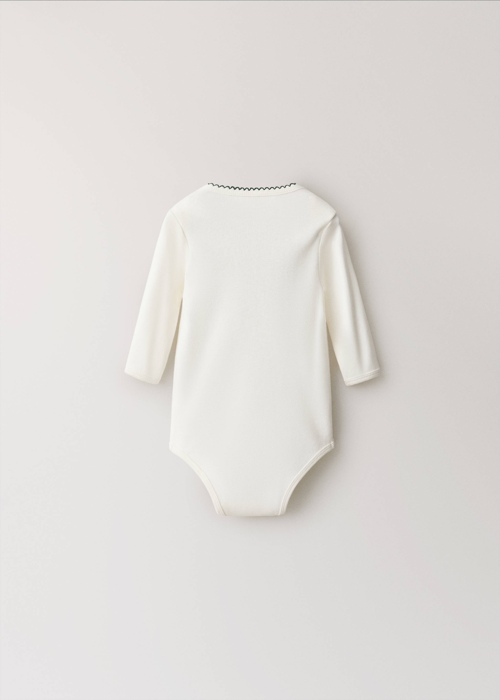 Off-white long-sleeved baby body with dark scalloped neckline trim, back view.