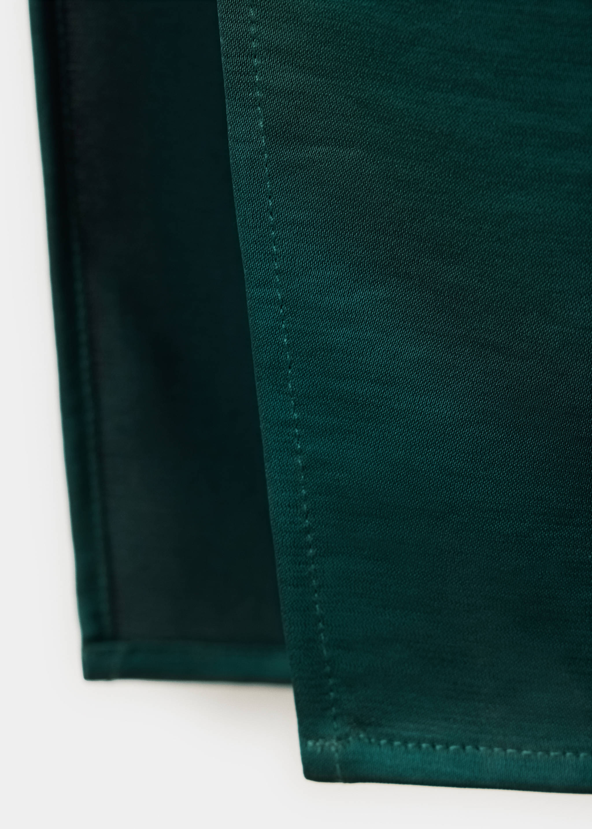 Dark green dress fabric detail showing smooth texture and seams.