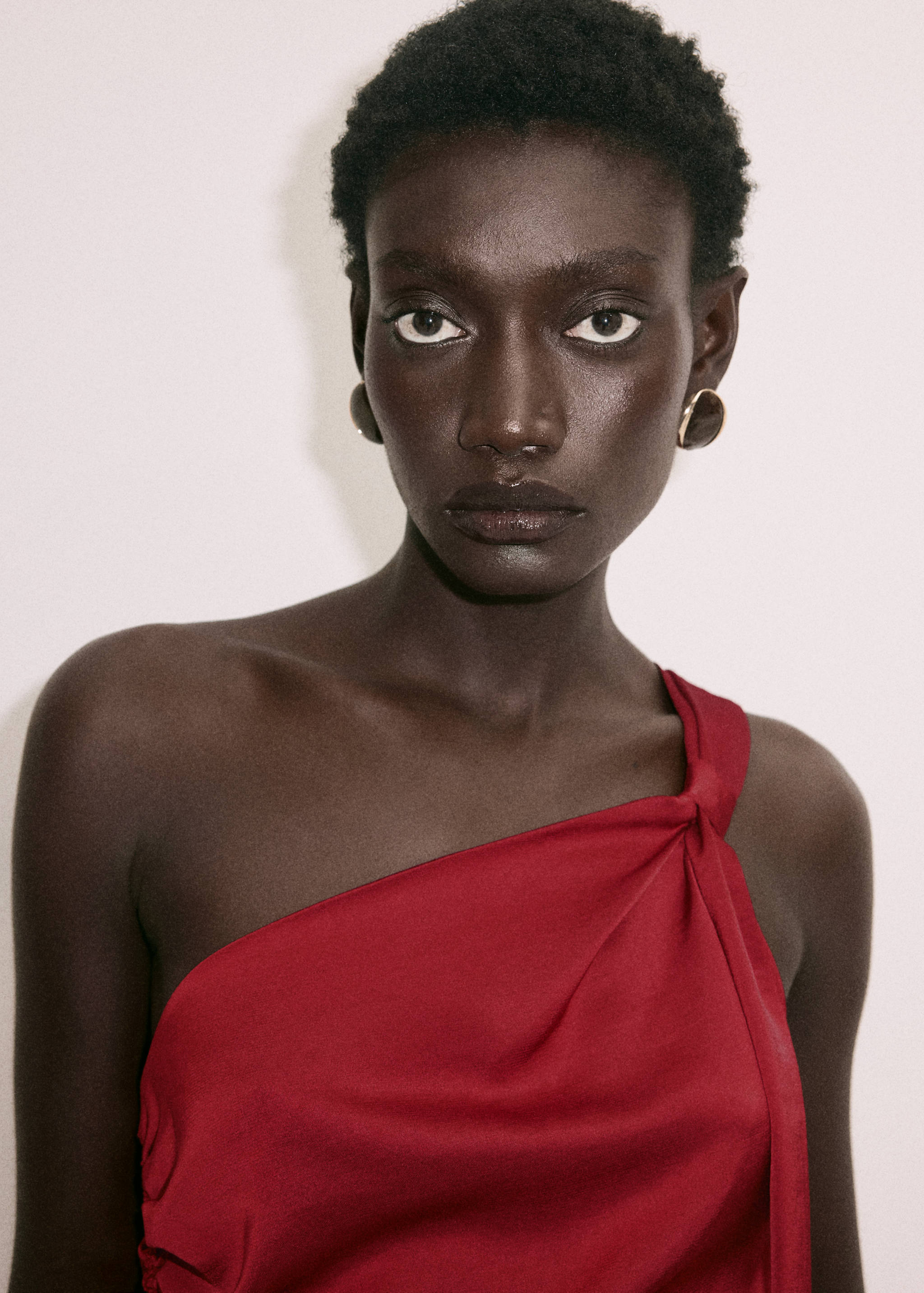 Close-up of a dark red one-shoulder dress with a knotted strap.