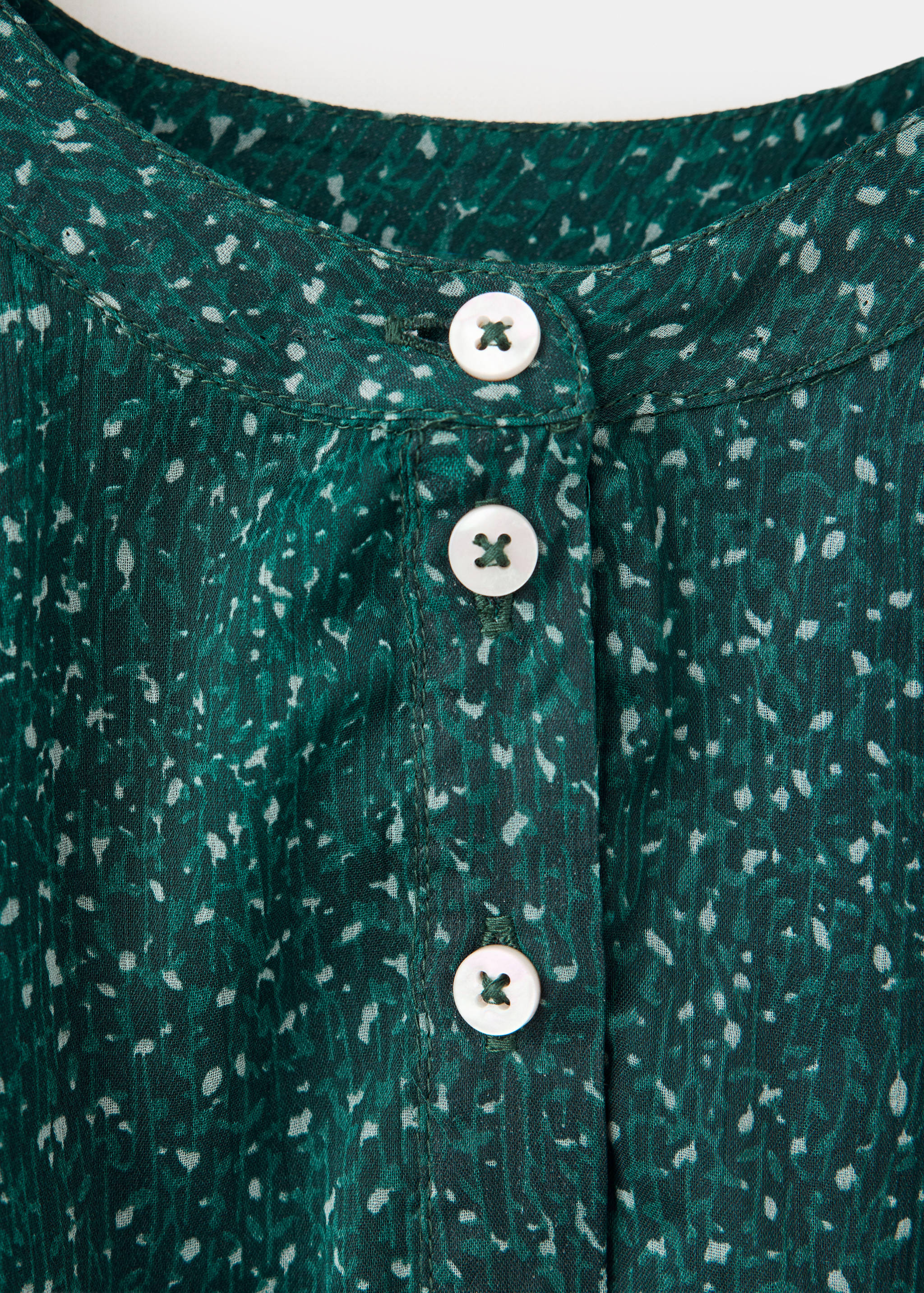 Close-up of a green printed dress neckline with white buttons.