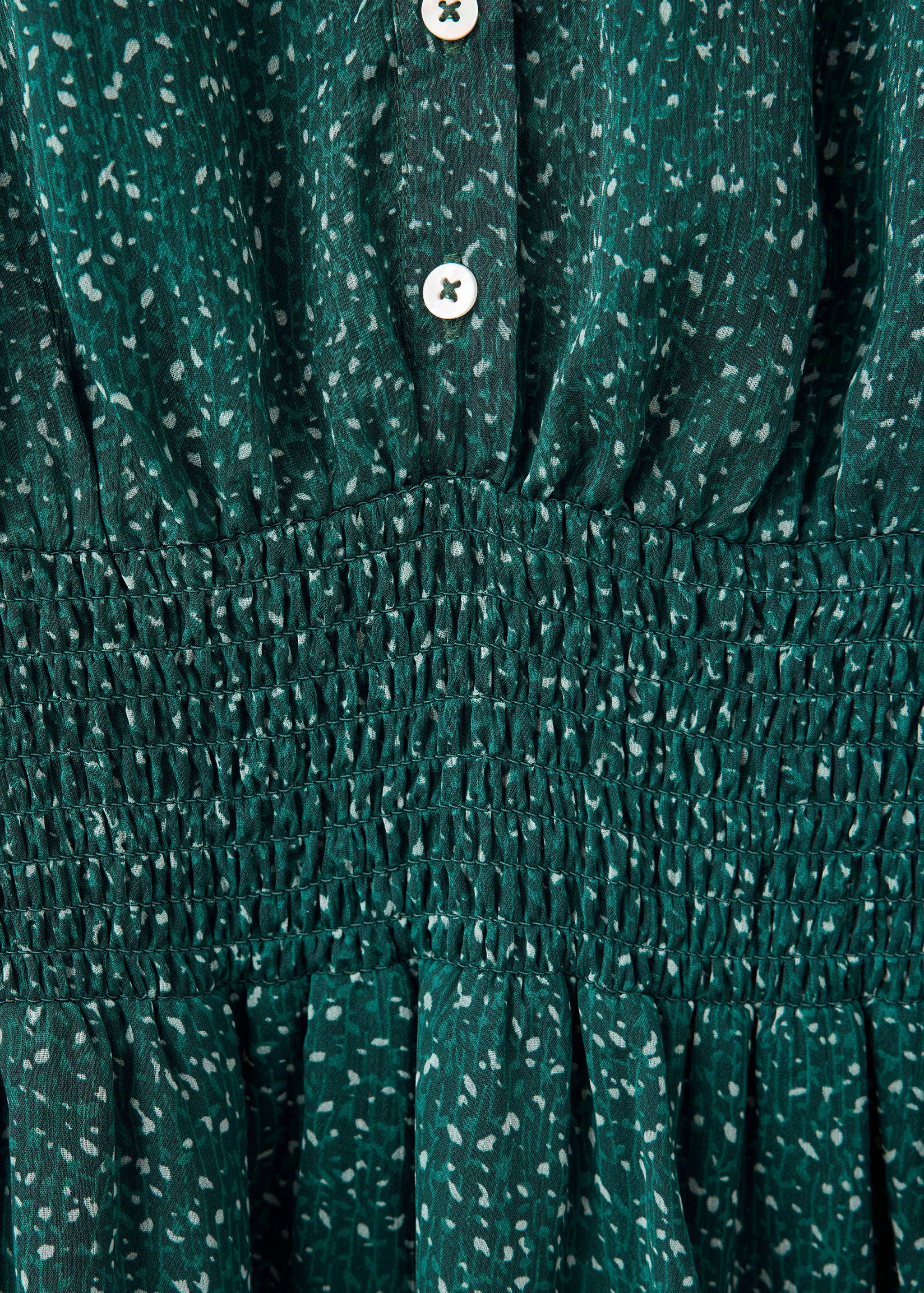 Green speckled dress fabric detail with a smocked waist and buttons