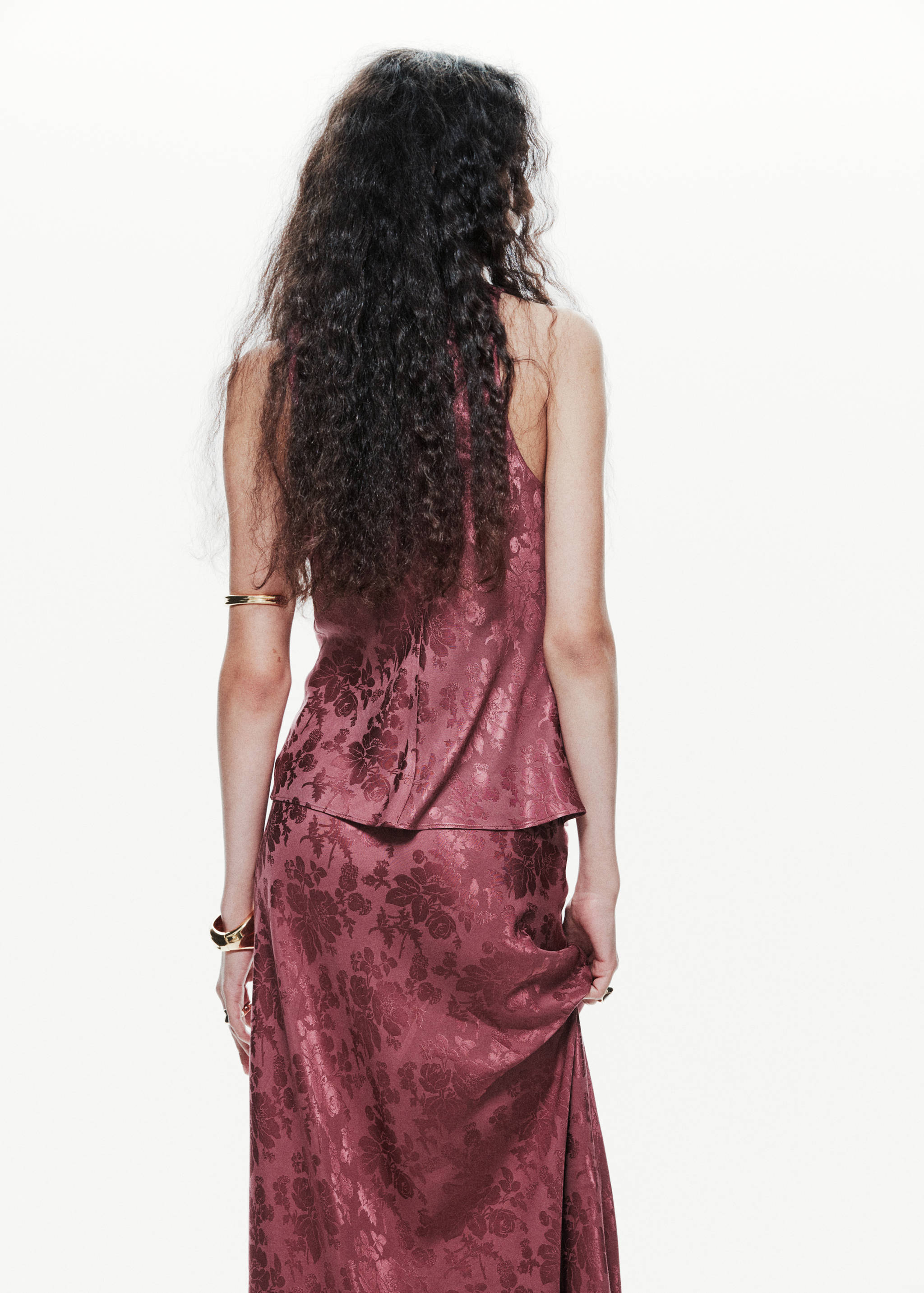 Plum floral jacquard blouse worn from the back, paired with a matching skirt.