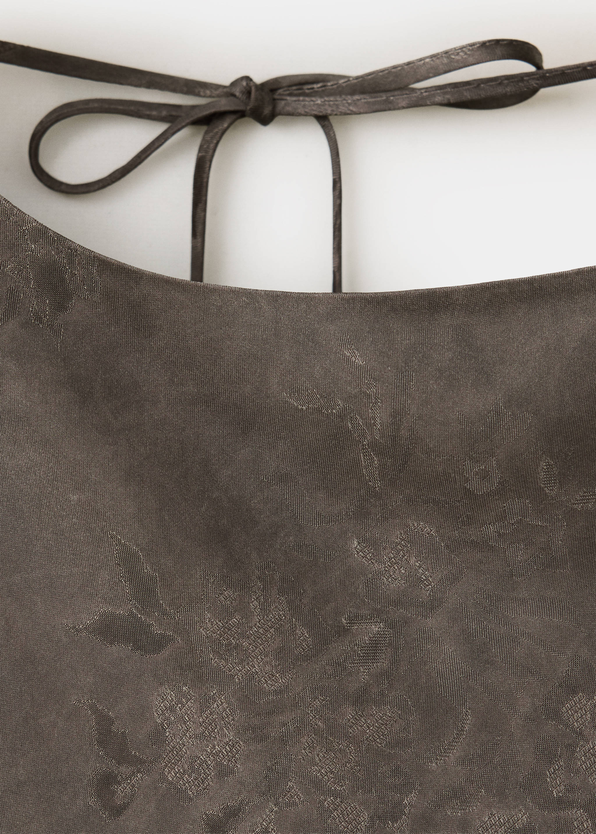 Dark brown dress detail with tonal floral pattern and tie straps.