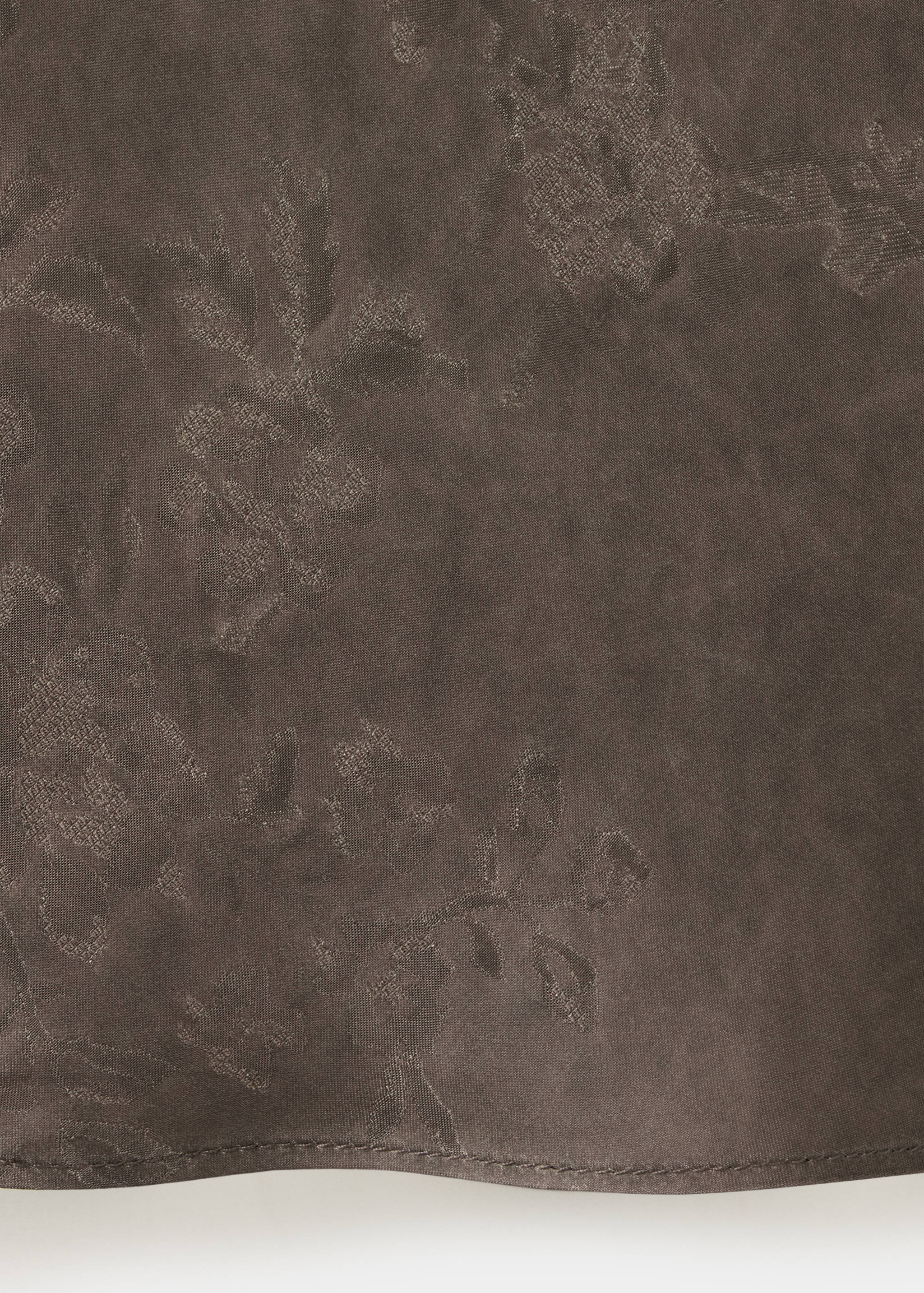 Close-up of brown dress fabric with tonal floral pattern.