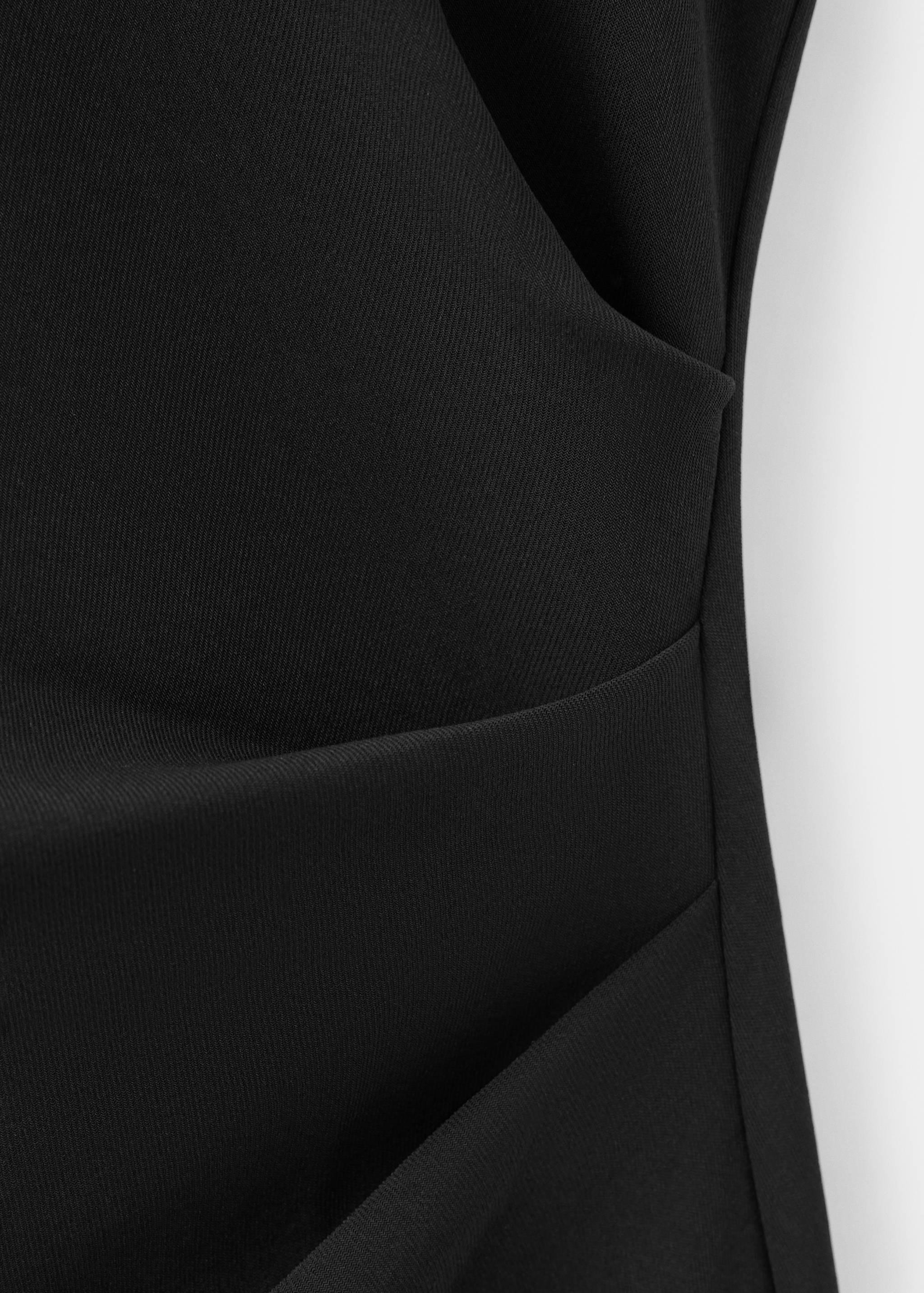 Close-up of fabric texture and draped detail on a black dress.