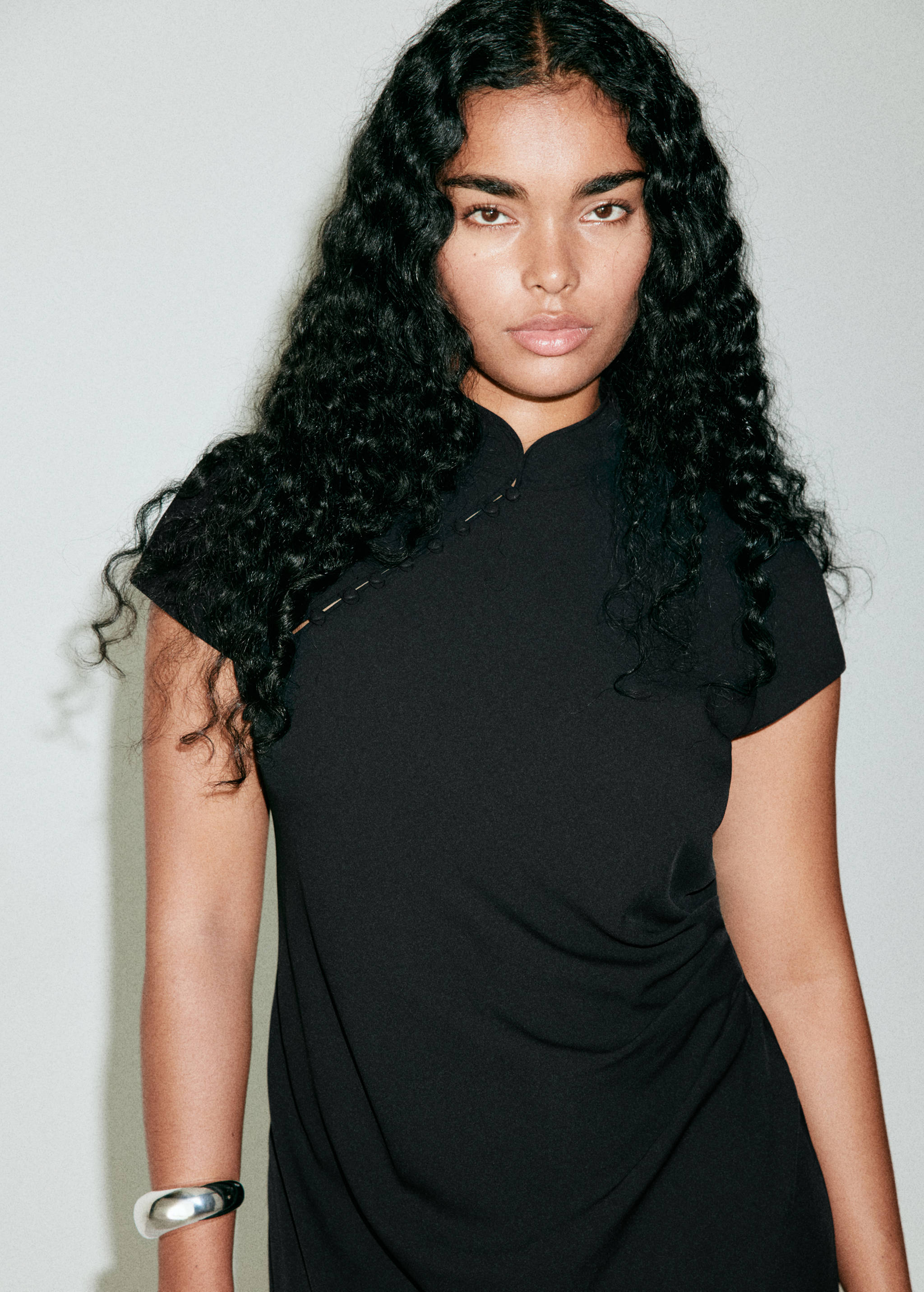 Black dress with mandarin collar and diagonal button placket.