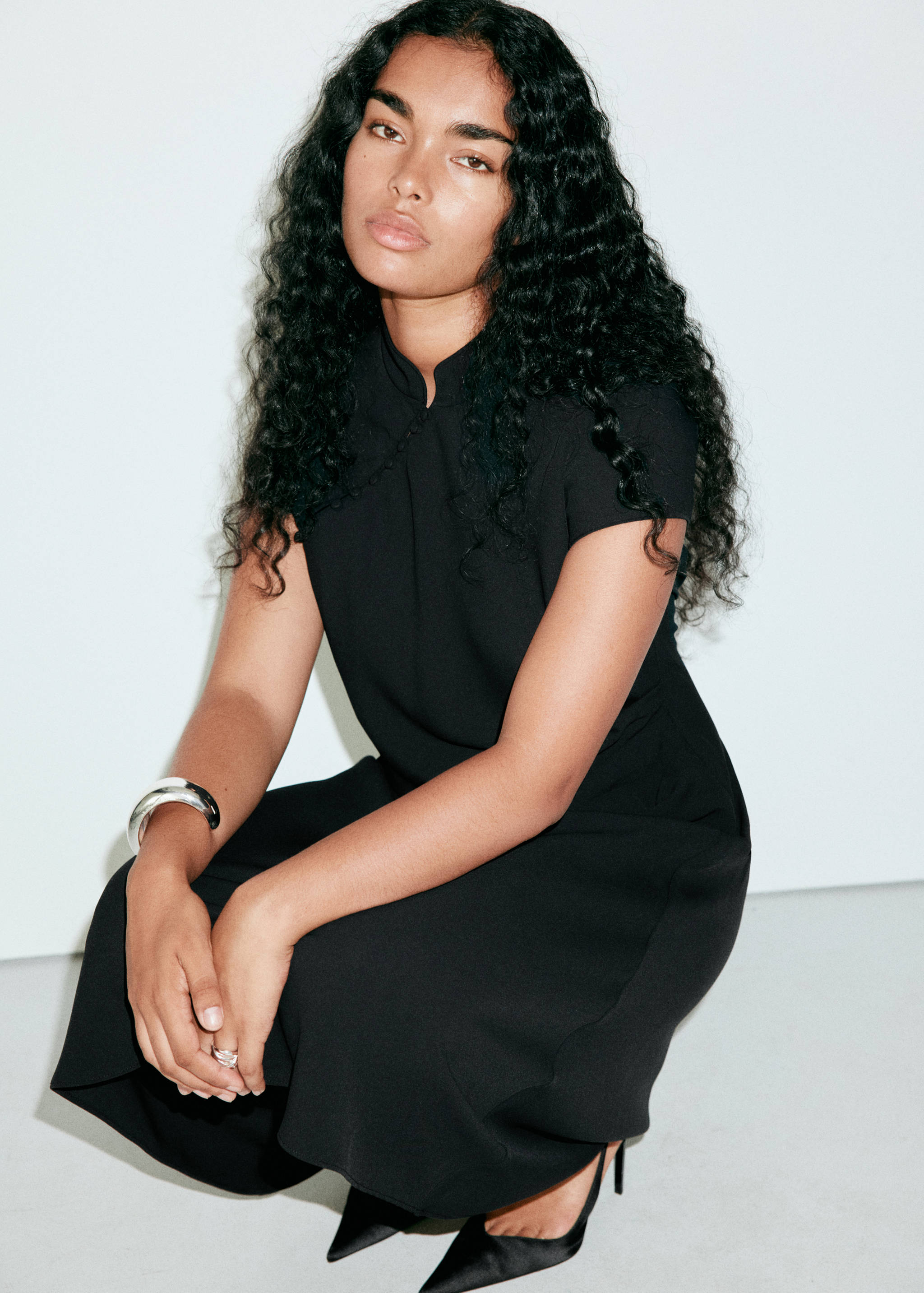 Black dress with short sleeves, mandarin collar, and diagonal button detail.