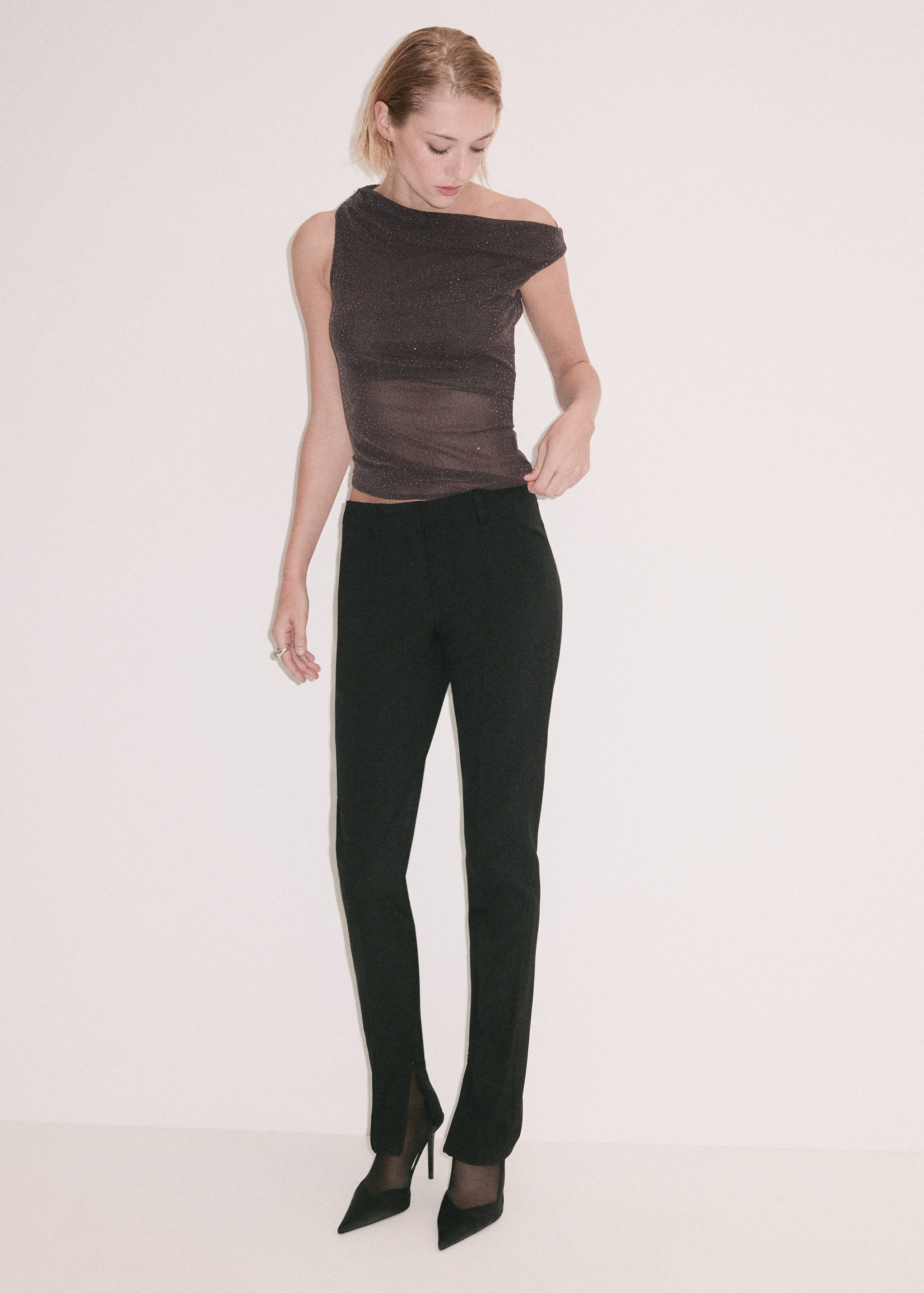 Brown asymmetrical one-shoulder top paired with black trousers