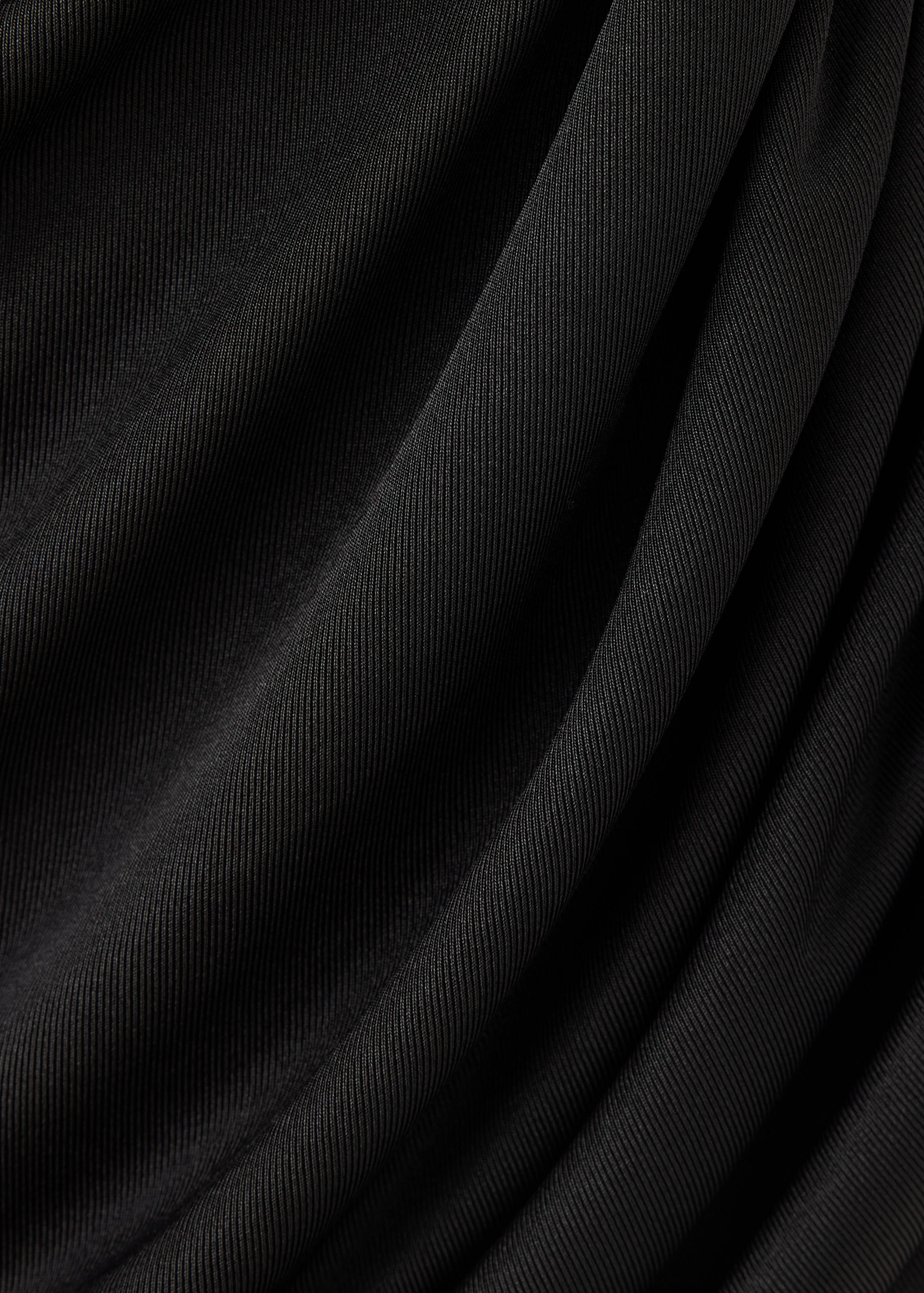 Close-up of a black ribbed top detail showing soft draping.