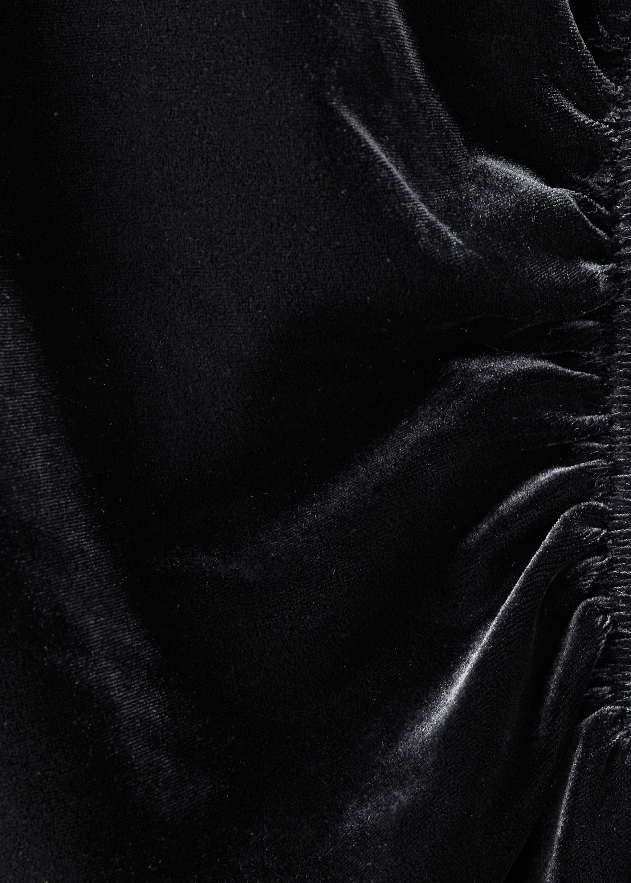 Close-up of a black velvet dress featuring gathered ruching.
