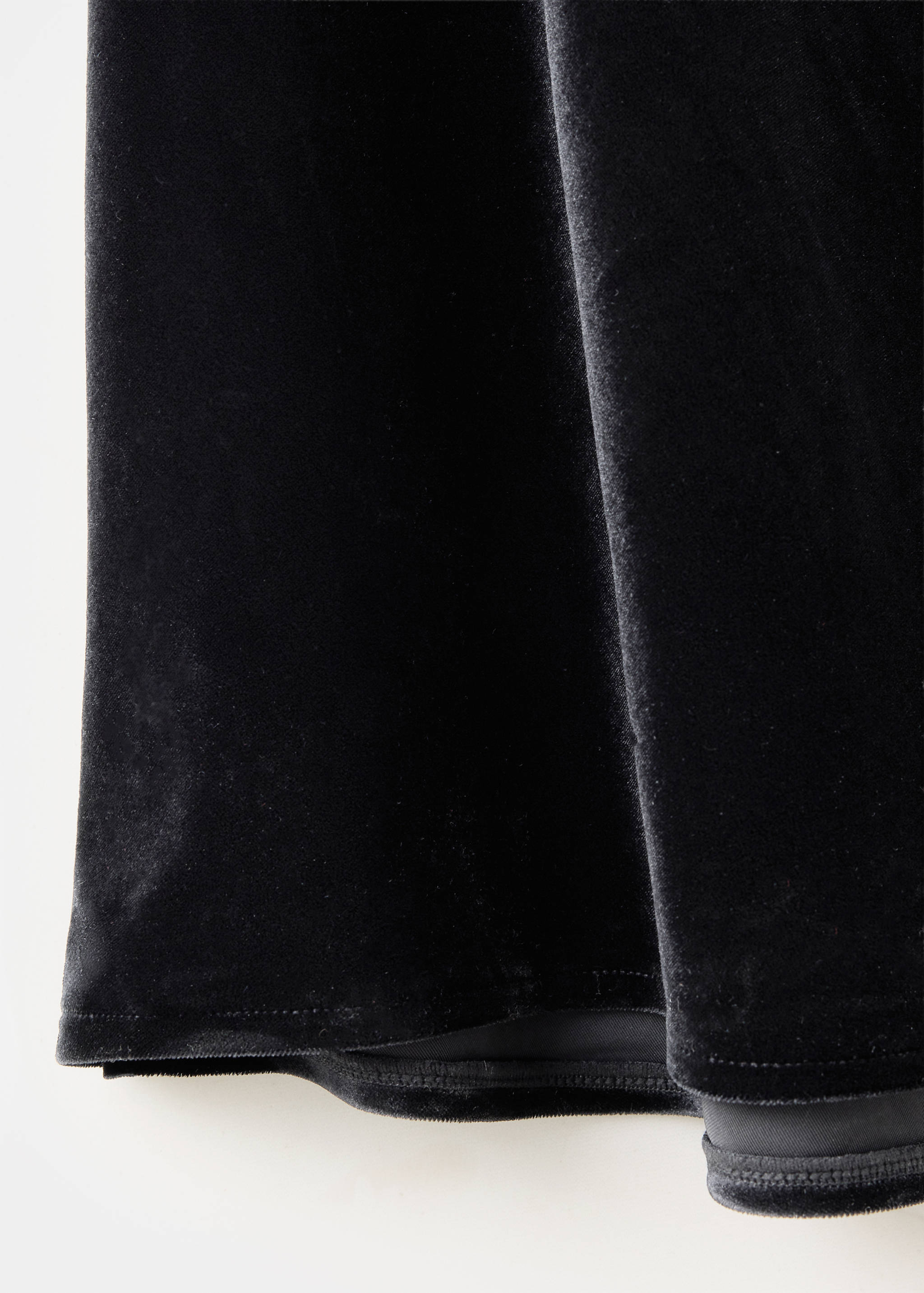 Close-up of a black velvet dress fabric showing texture and hem.