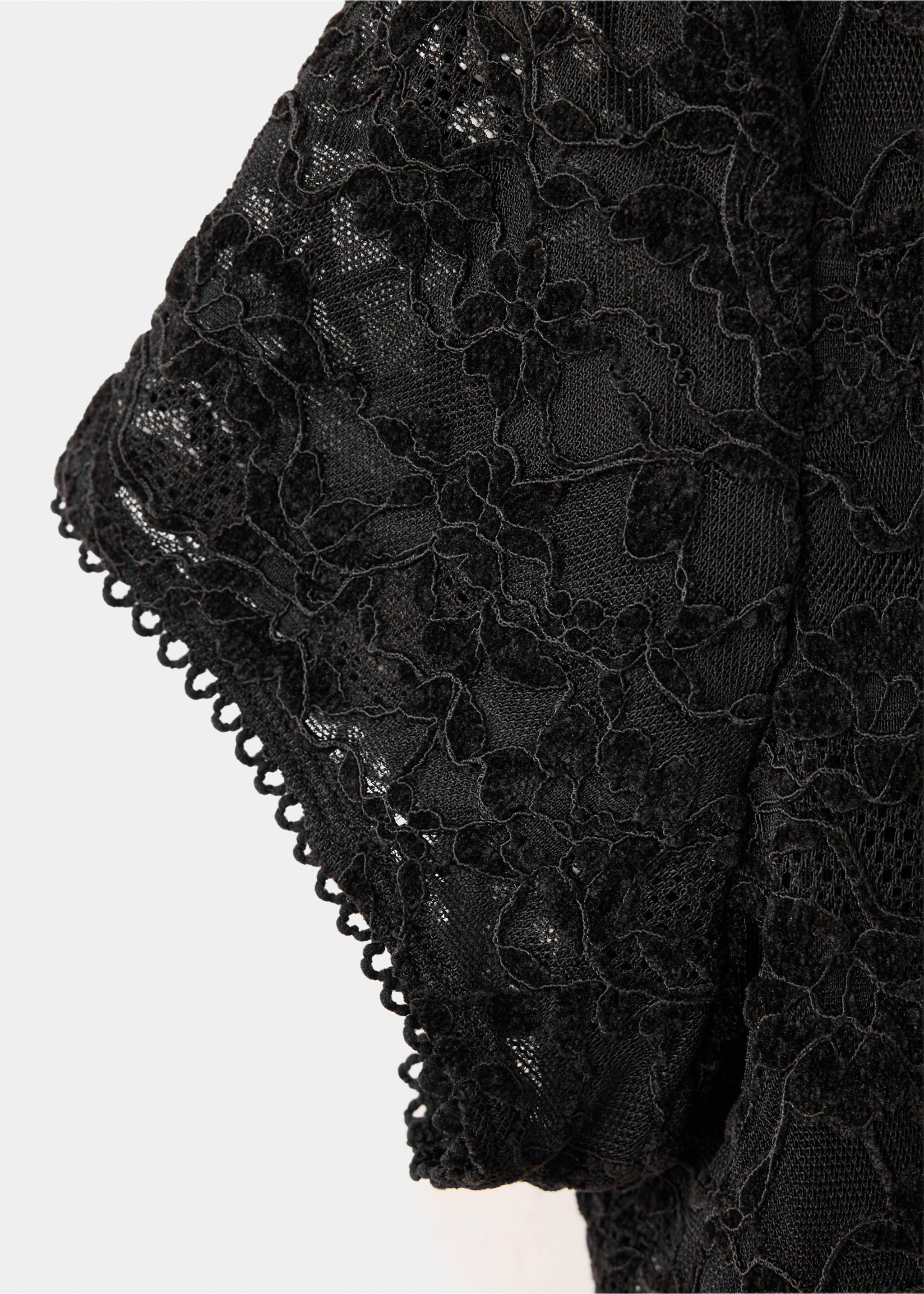 Close-up of the black top with floral lace fabric and a scalloped sleeve edge., Black. Ref: 37029134-00.