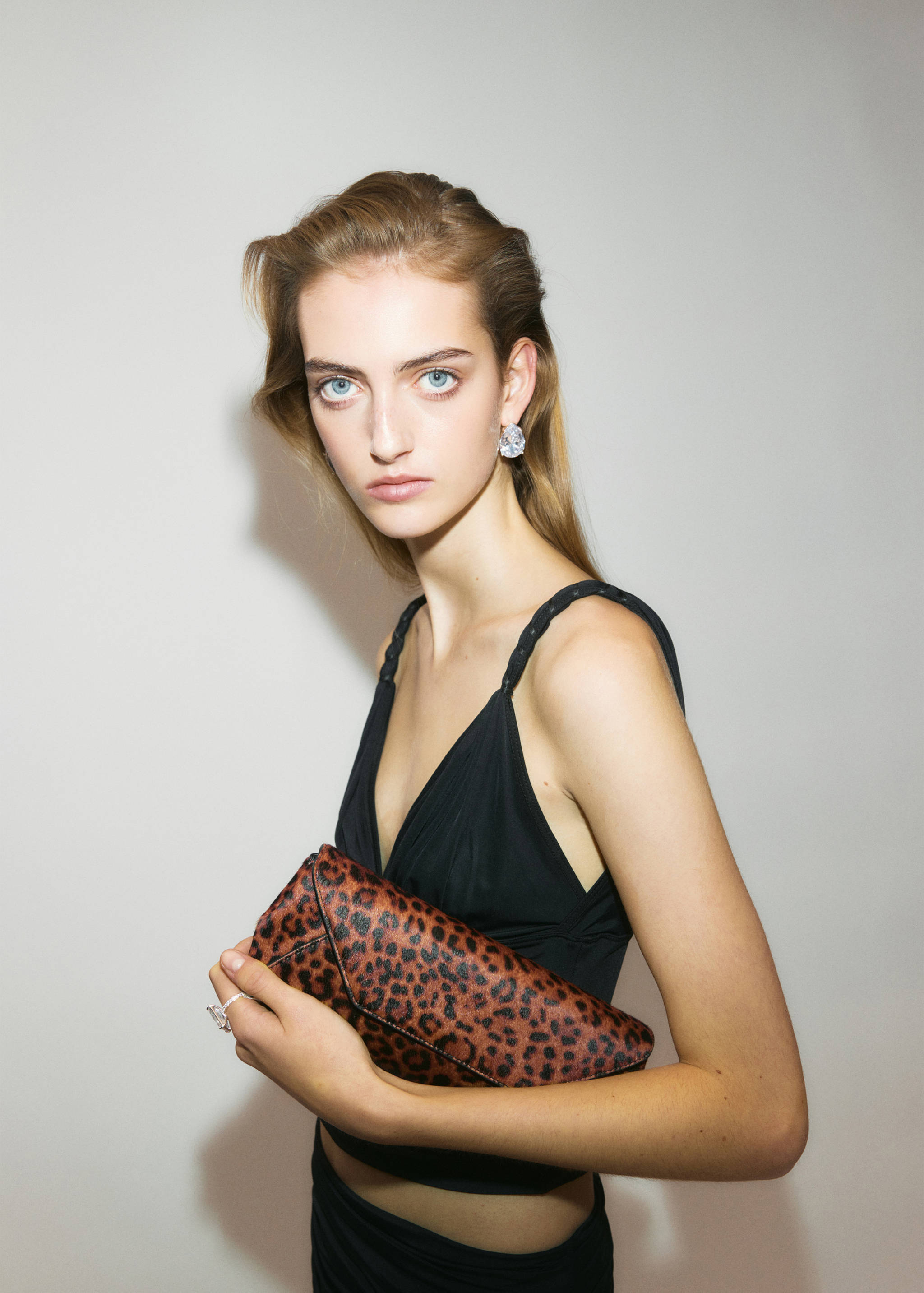 Brown and black leopard-print clutch bag held by a model.