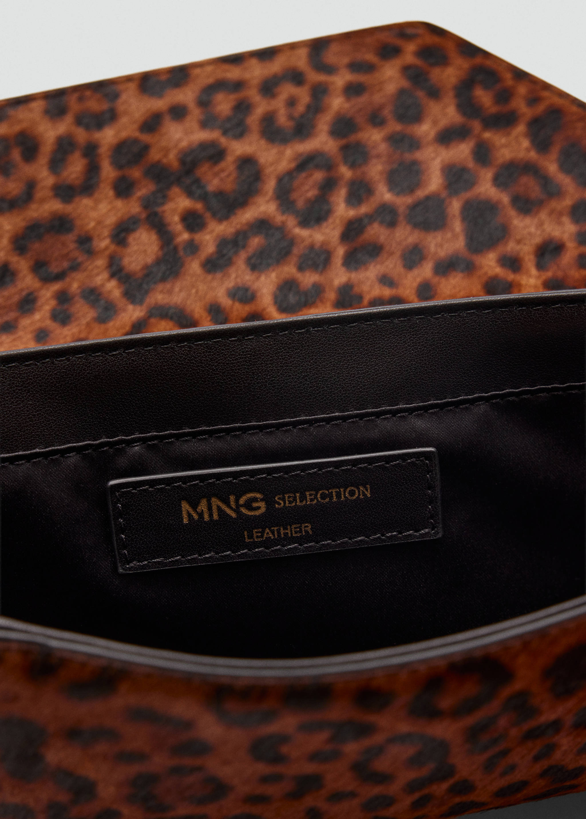Close-up interior of a leopard-print leather handbag showing its dark lining and brand label.