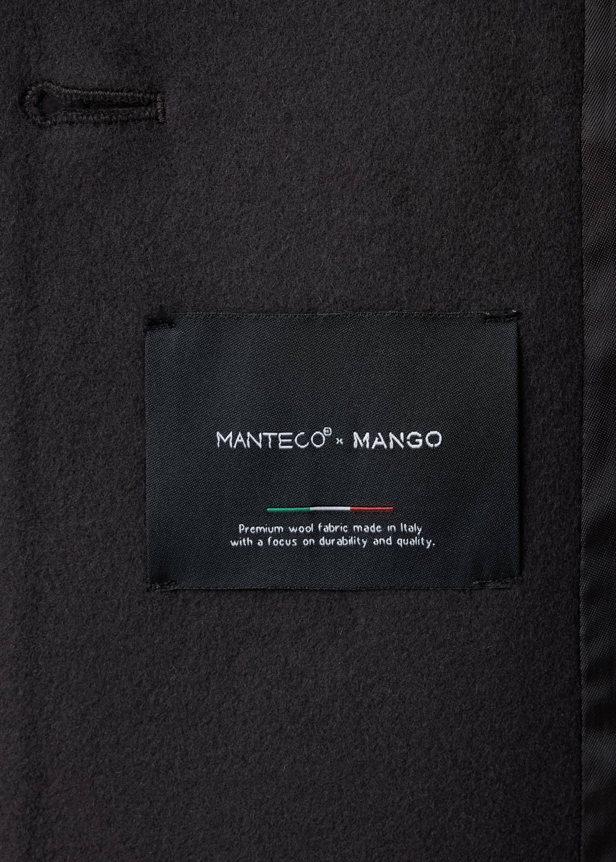 Close-up of the black coat fabric showing the MANTECO x MANGO interior label.