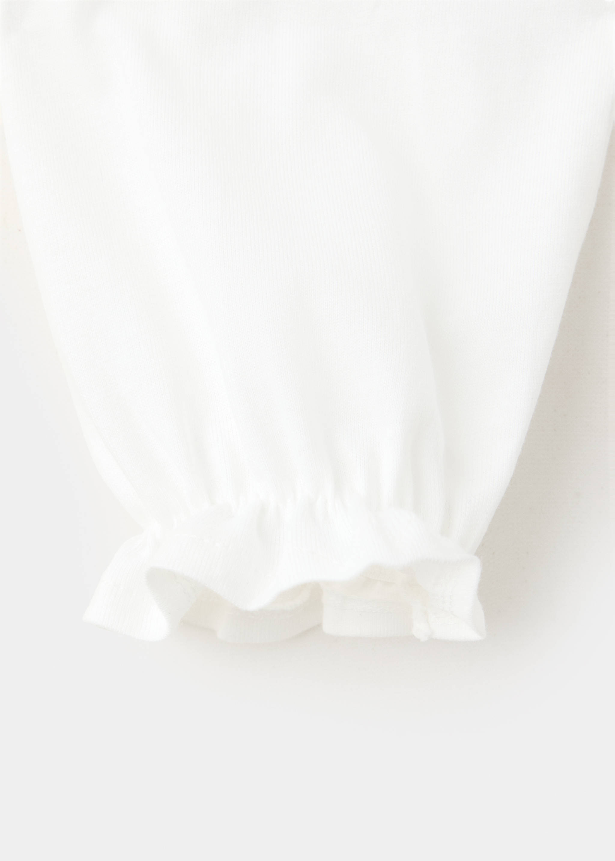 White t-shirt fabric detail featuring a ruffled elastic sleeve cuff.
