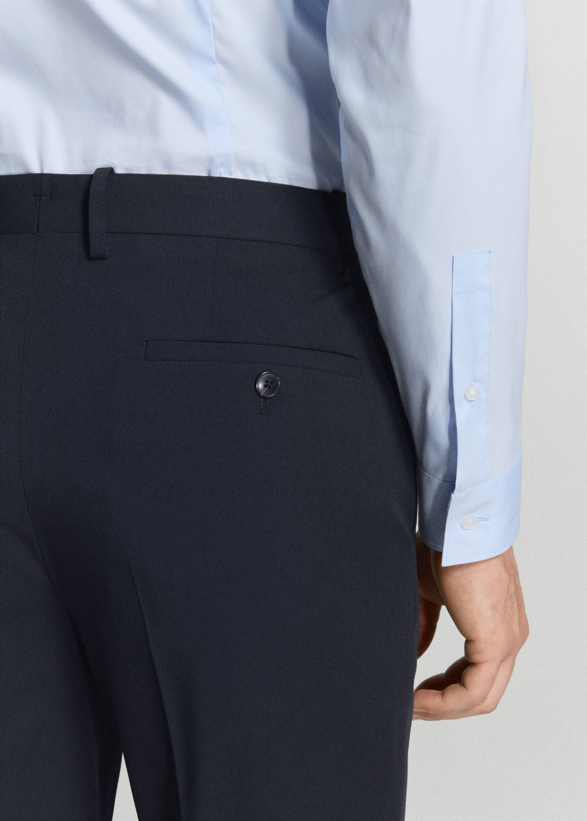 Navy blue trousers featuring belt loops and a single-welt back pocket with a button closure.