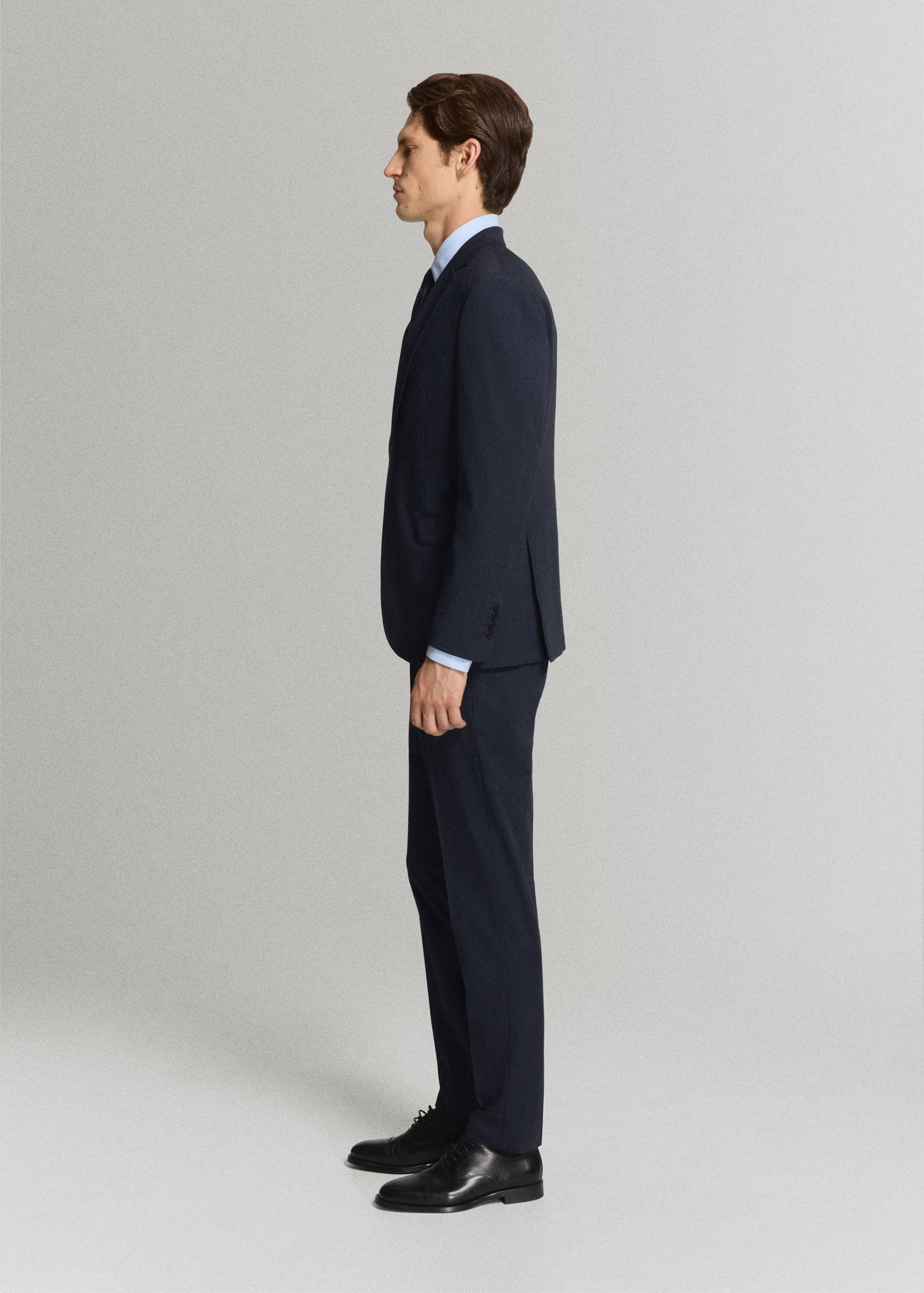 Navy blue trousers worn with a matching blazer, light blue shirt, and dark tie.