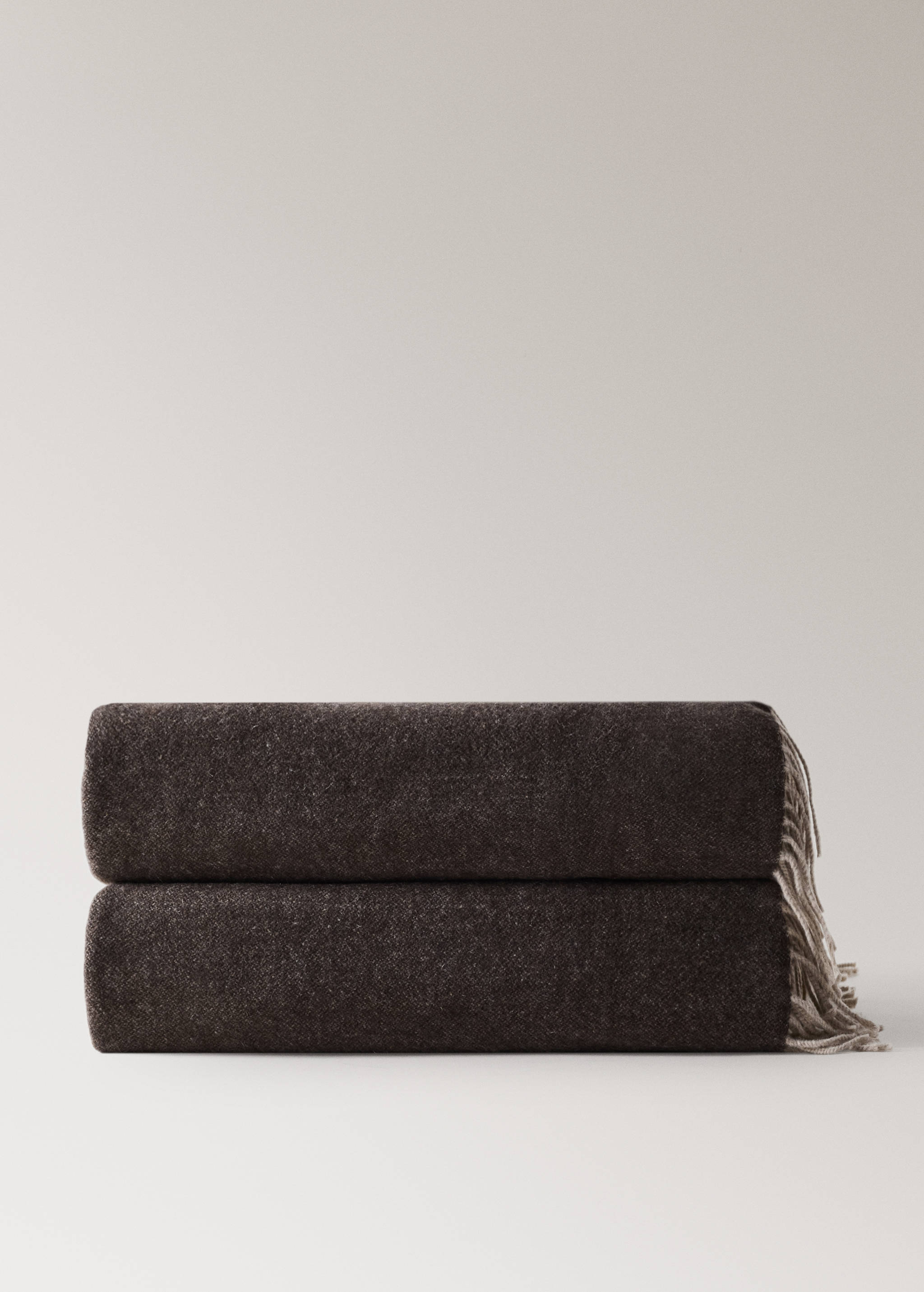 Brown textured blanket with fringe detail, folded neatly.
