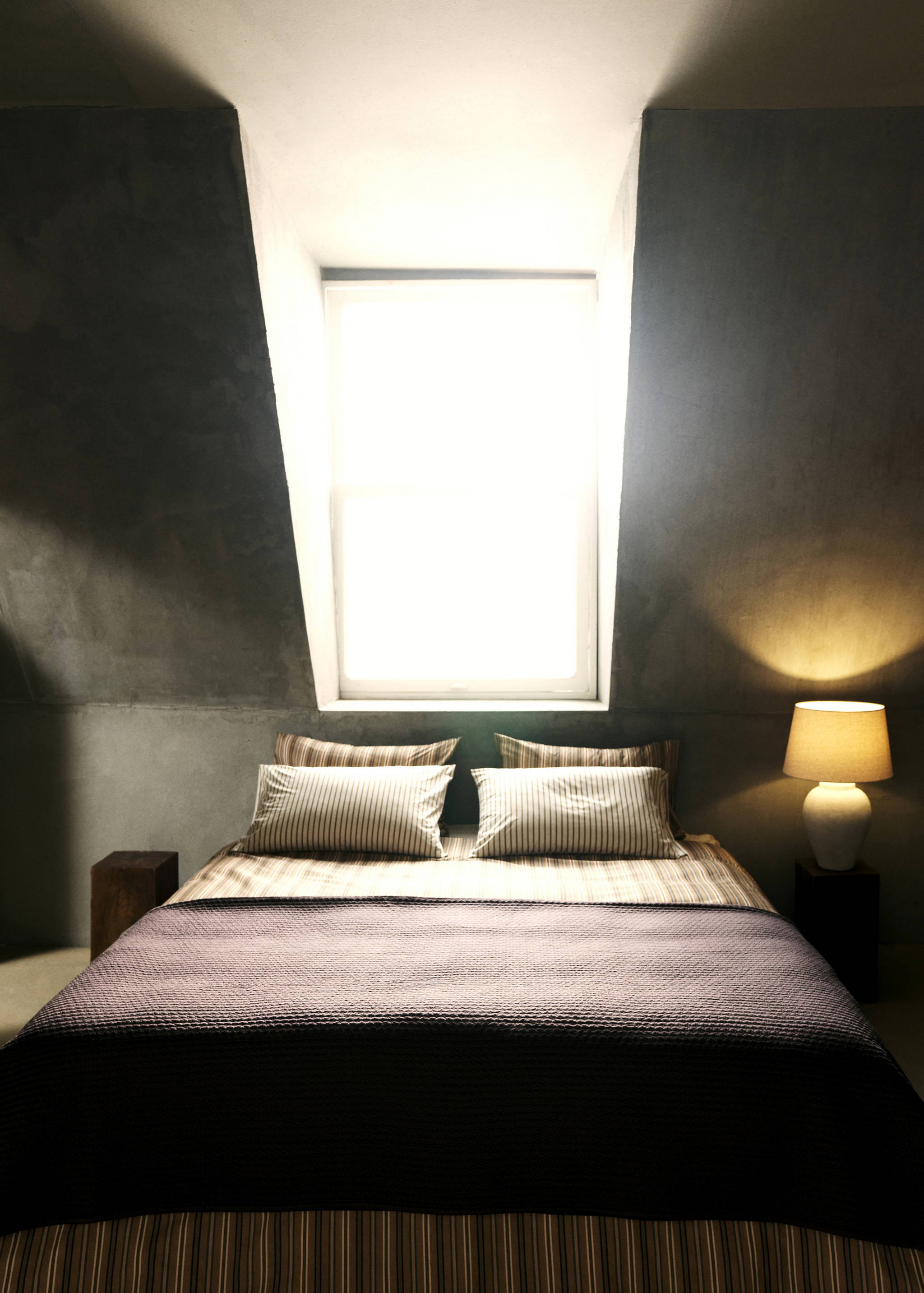 Dark plum quilted duvet on a bed with striped bedding.