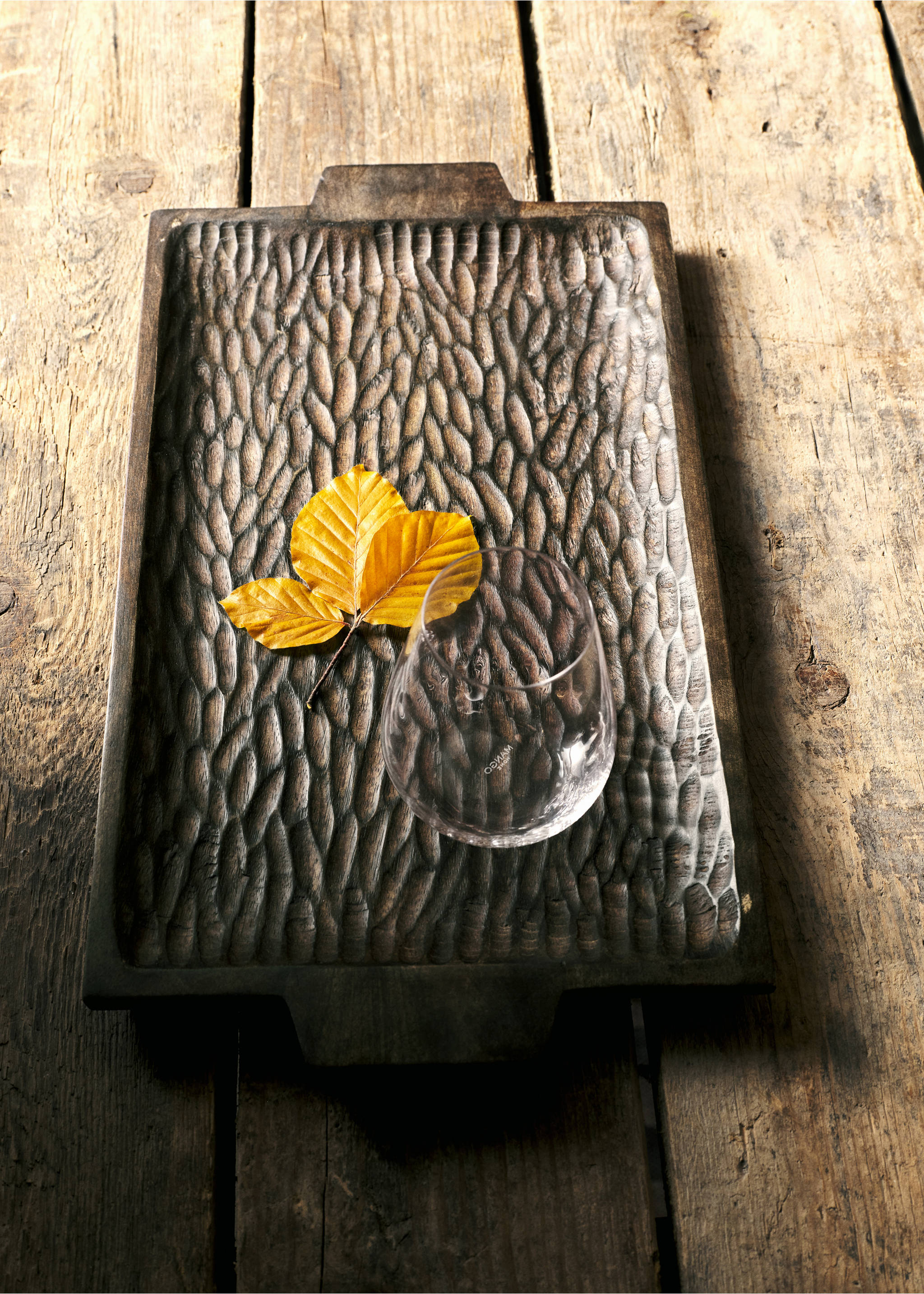 Dark wooden decorative tray with carved texture, styled with autumn leaves and a glass., Chocolate. Ref: 37034084-00.