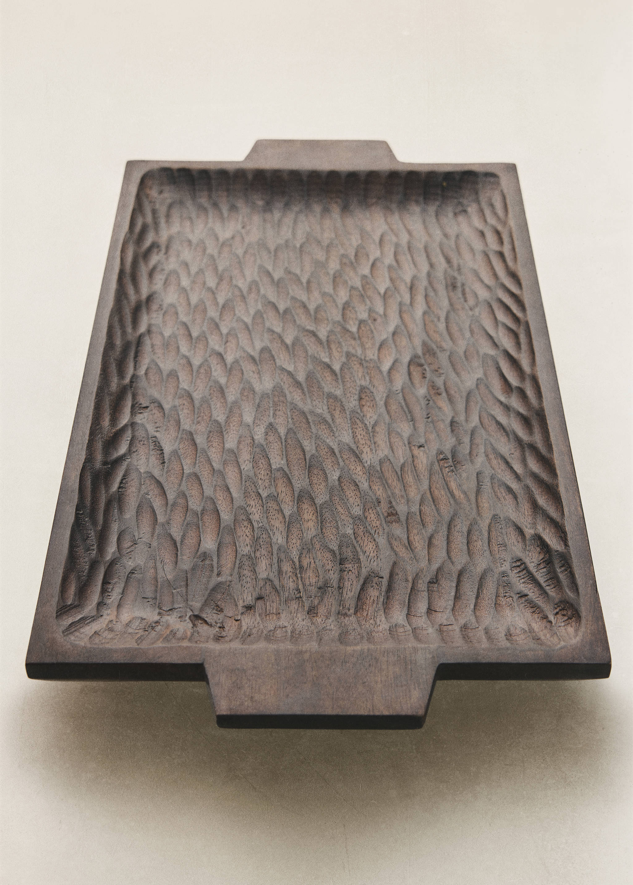 Dark wooden decorative tray with carved texture and handles.