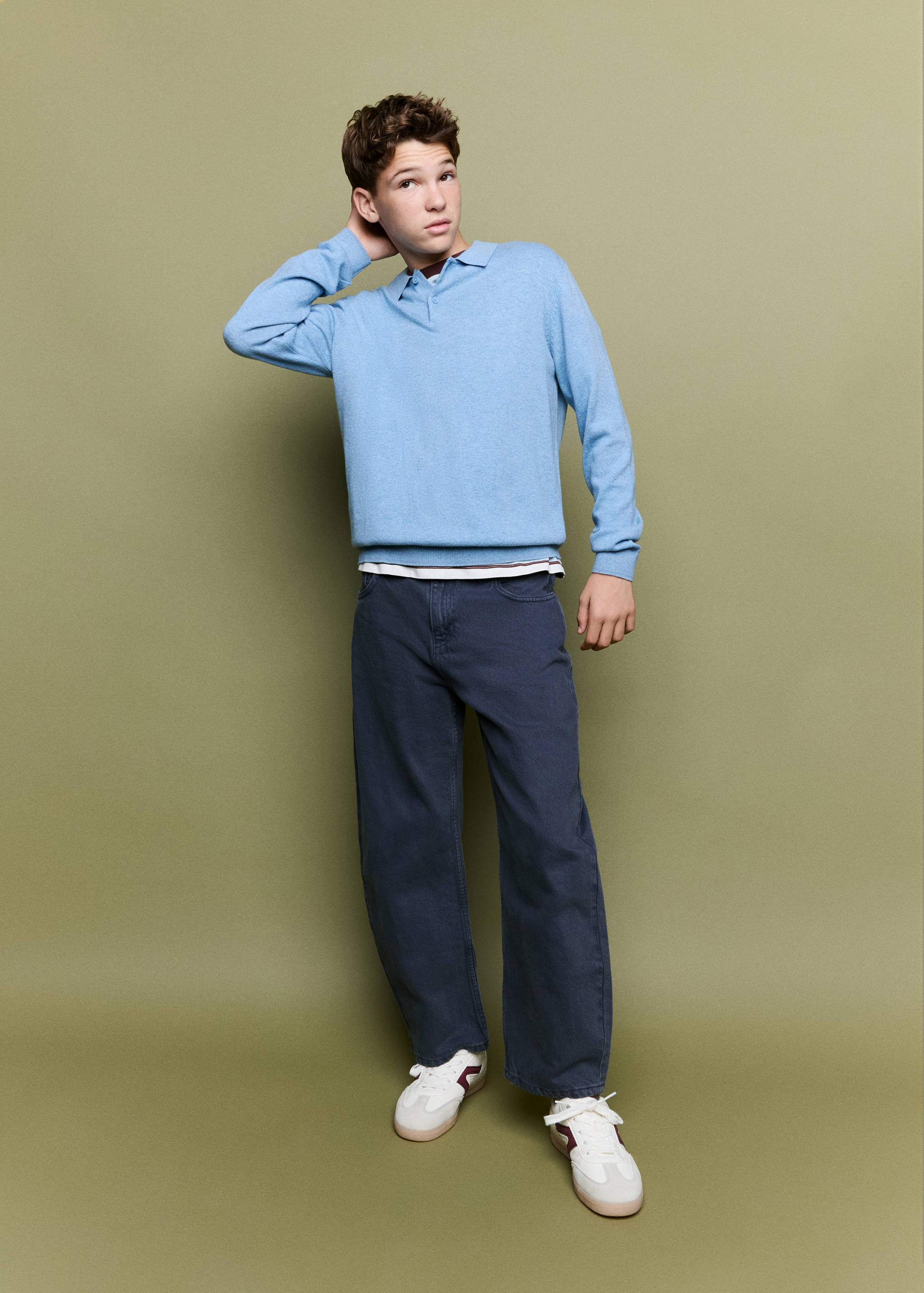 Polo de punto en azul claro con cuello y manga larga.