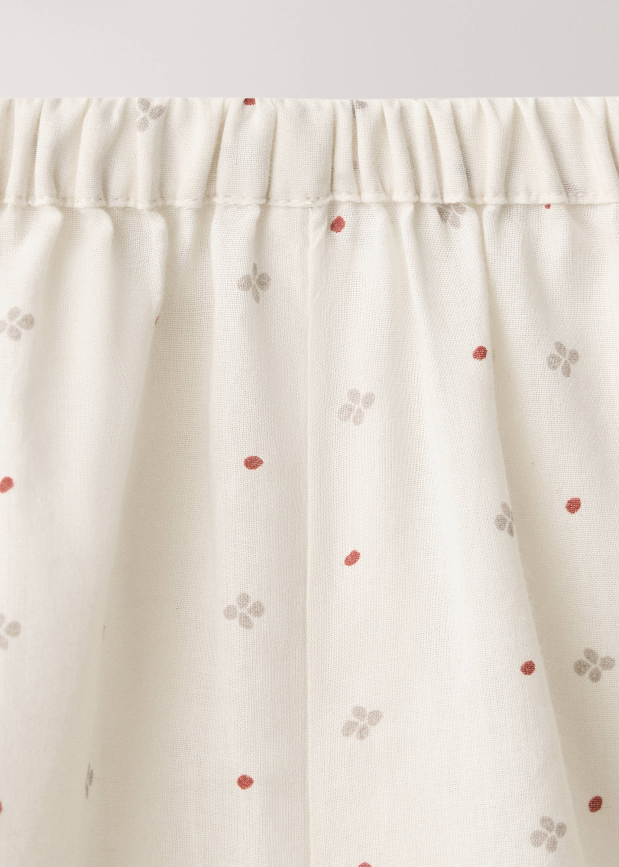 Close-up of the elasticated waistband on cream patterned pyjama trousers.