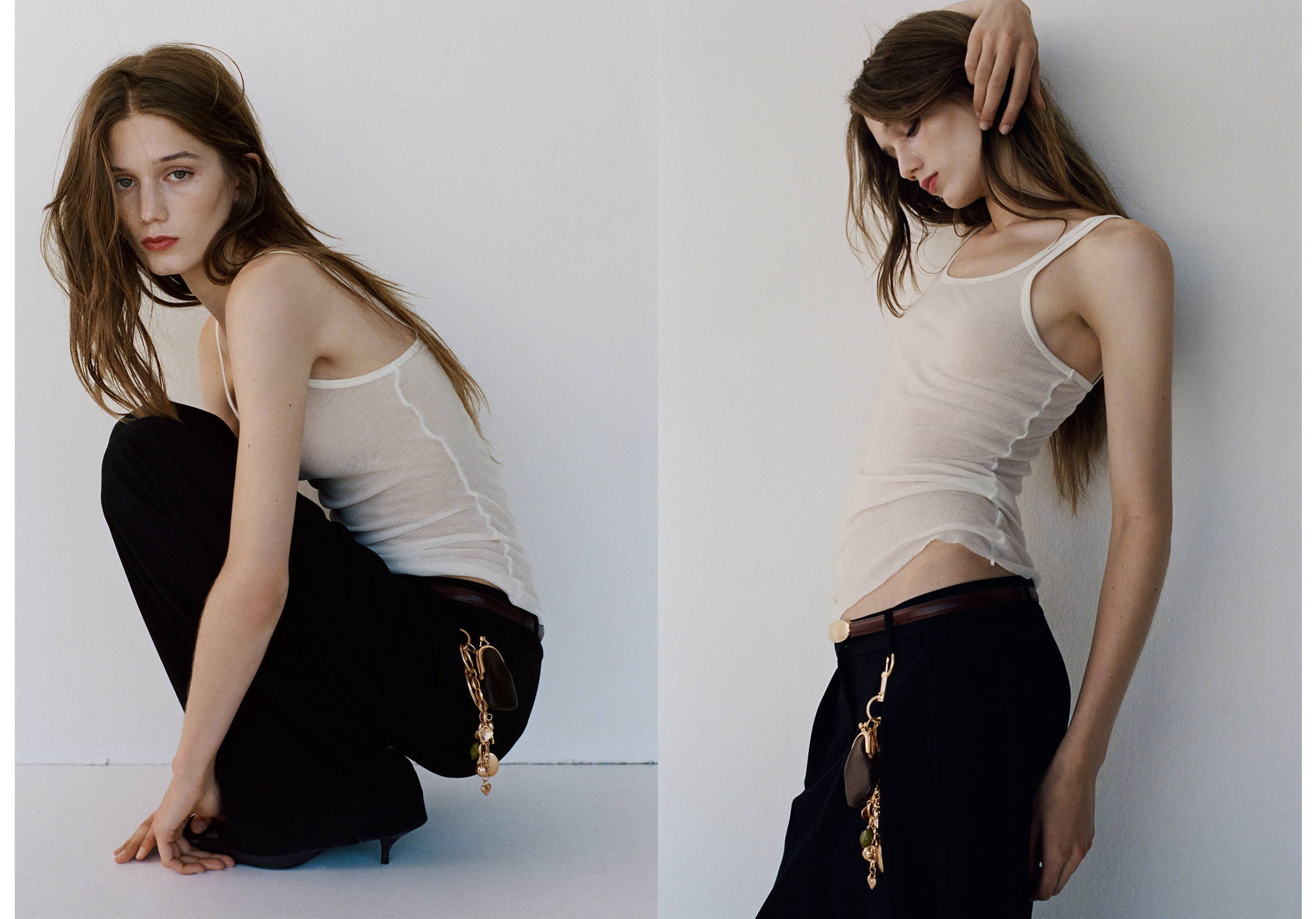 Gold-tone metal charm keychain worn on black trousers with a cream ribbed tank top.