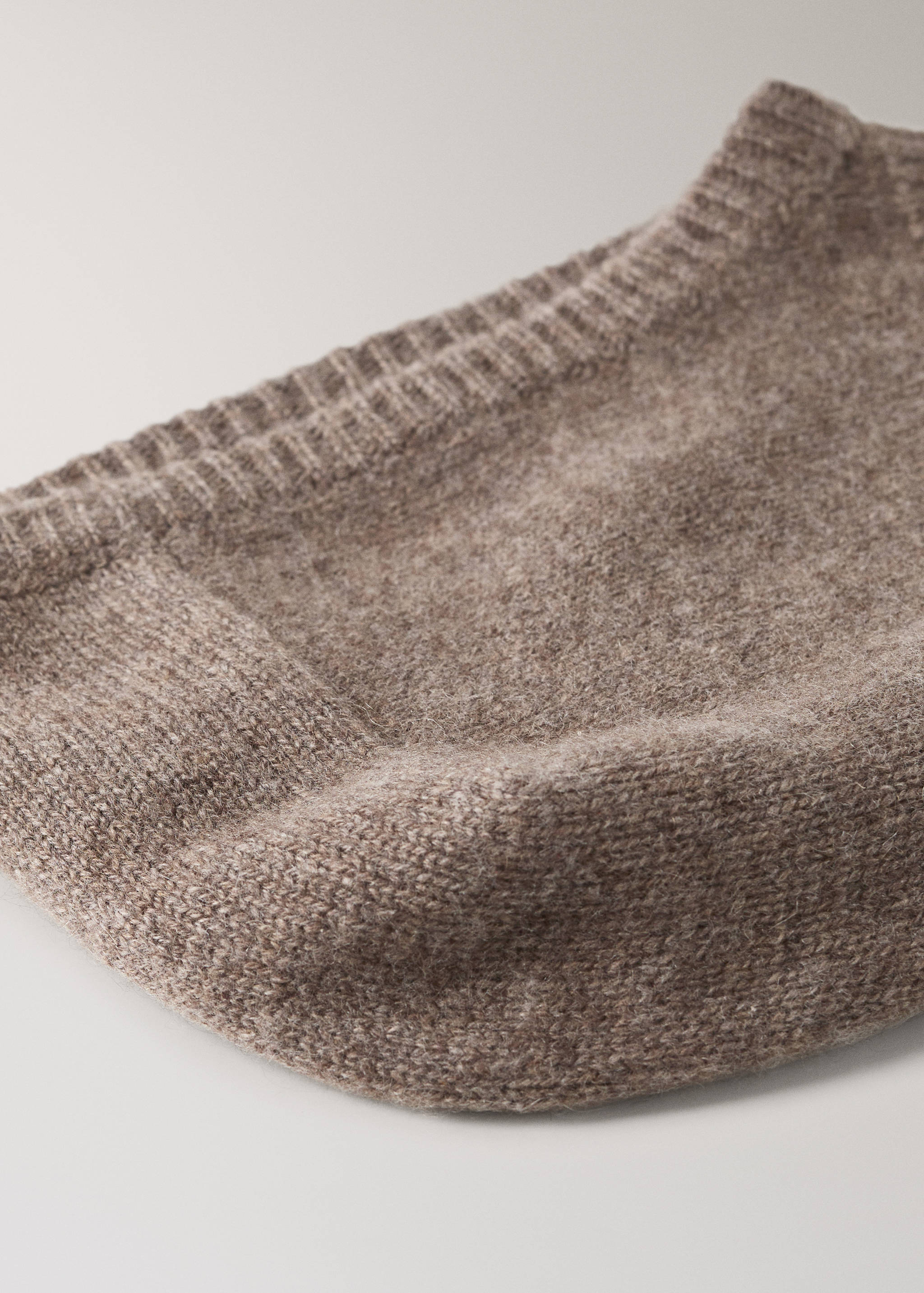 Detalle de gorro de punto marrón que muestra el tejido texturizado suave y el ribete de canalé.