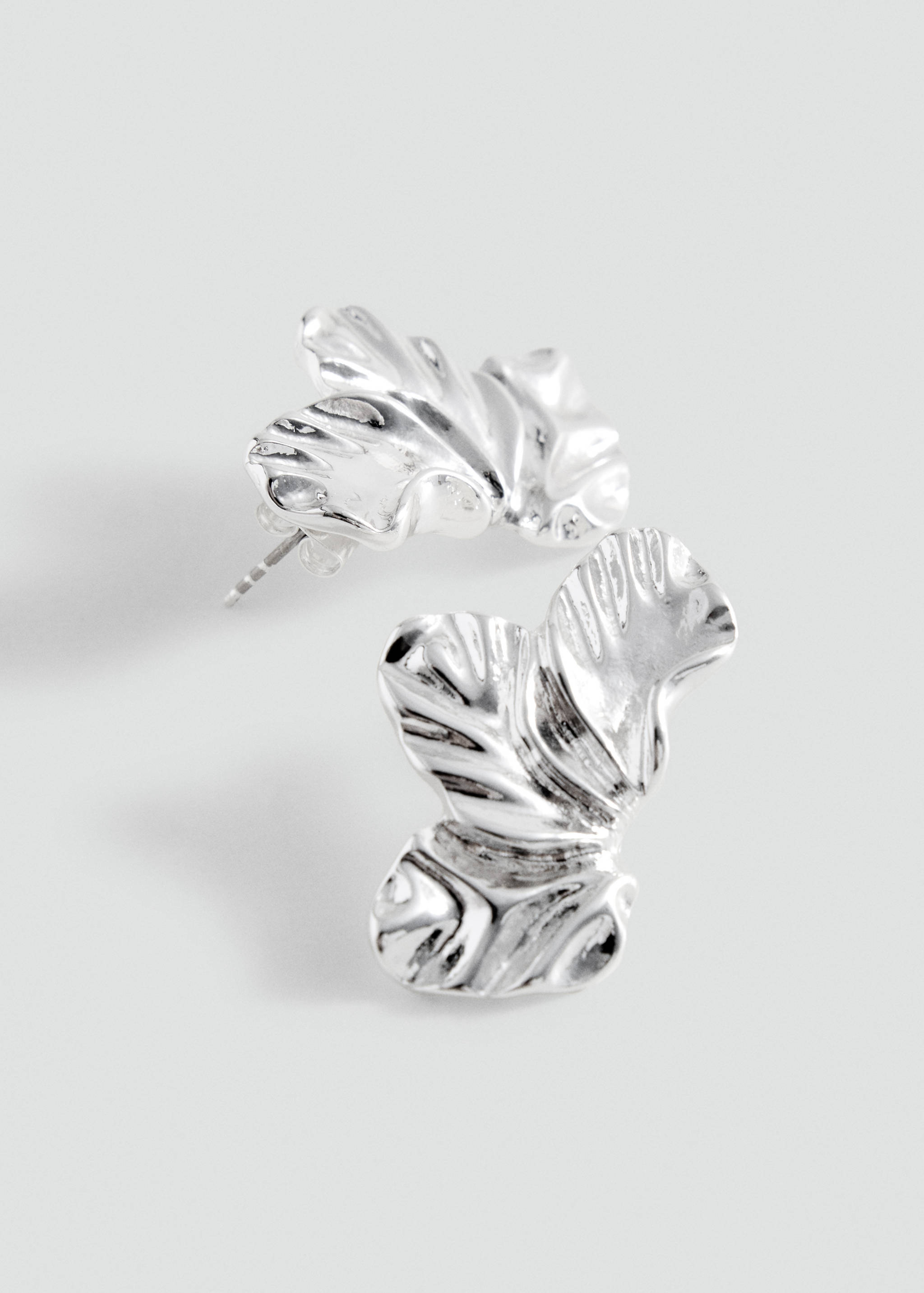 Silver earrings with an organic, textured leaf-like shape.