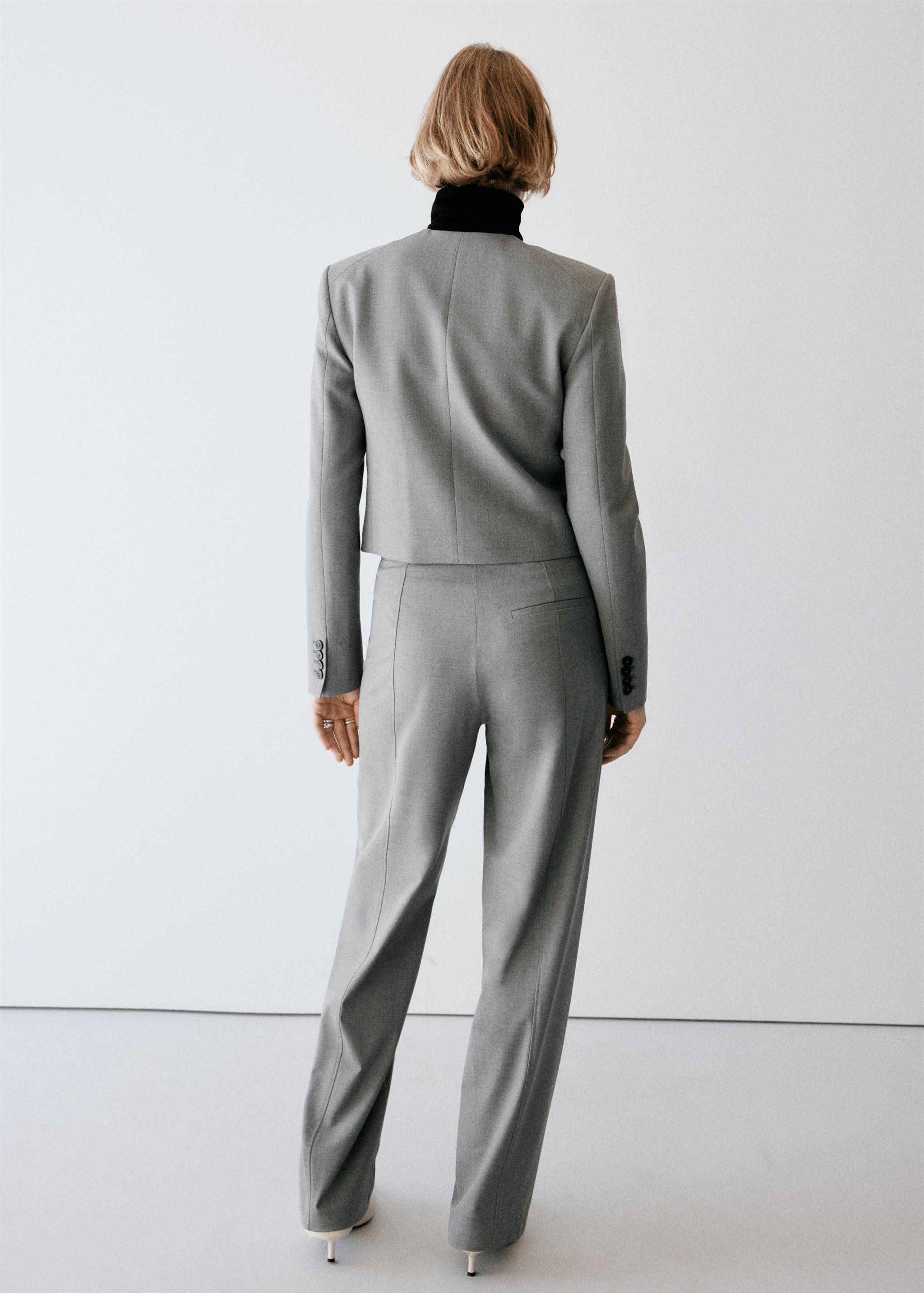 Grey trousers with straight fit and back welt pockets, shown from the back.