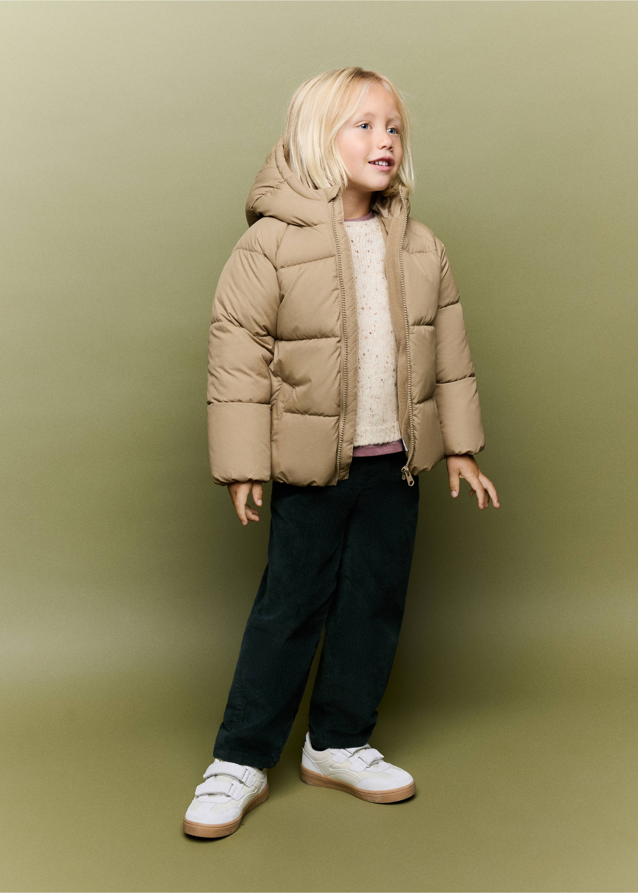 Beige quilted anorak with a hood worn by a child with dark green trousers and white trainers., Sand. Ref: 37035973-00.