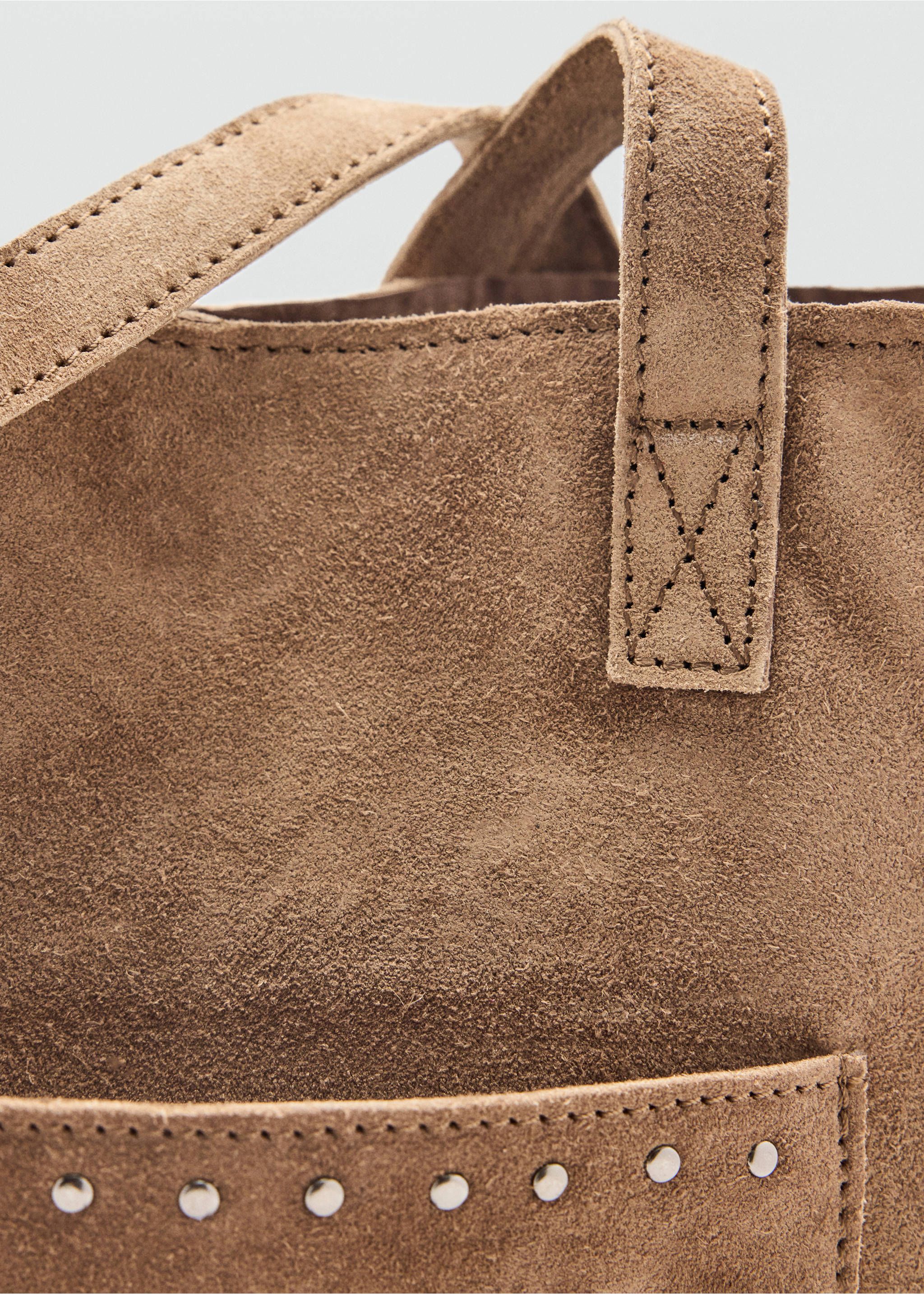 Close-up of a brown suede tote bag with metallic studs and top-stitching., Sand. Ref: 37035980-00.