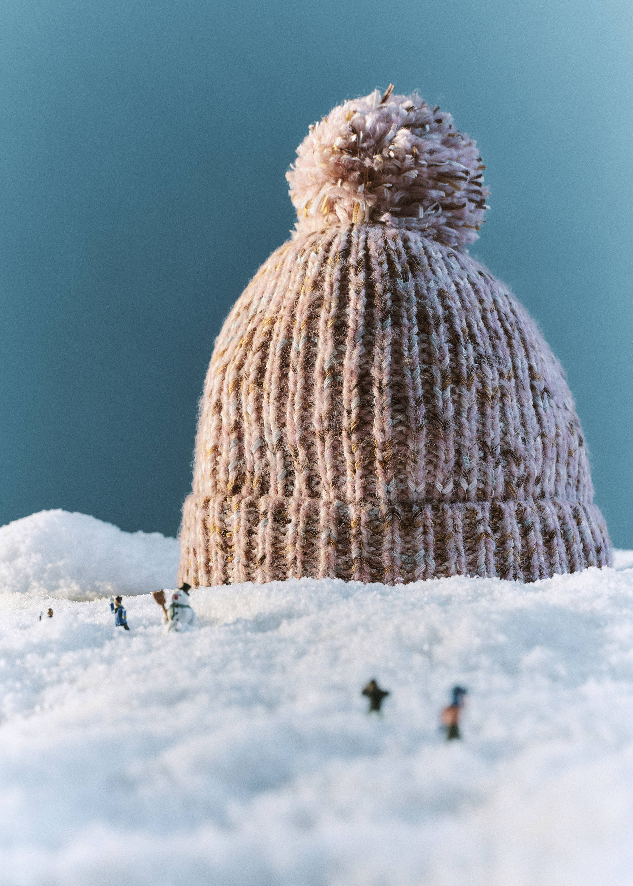 Pink ribbed knit beanie with a pom-pom in a snowy setting.