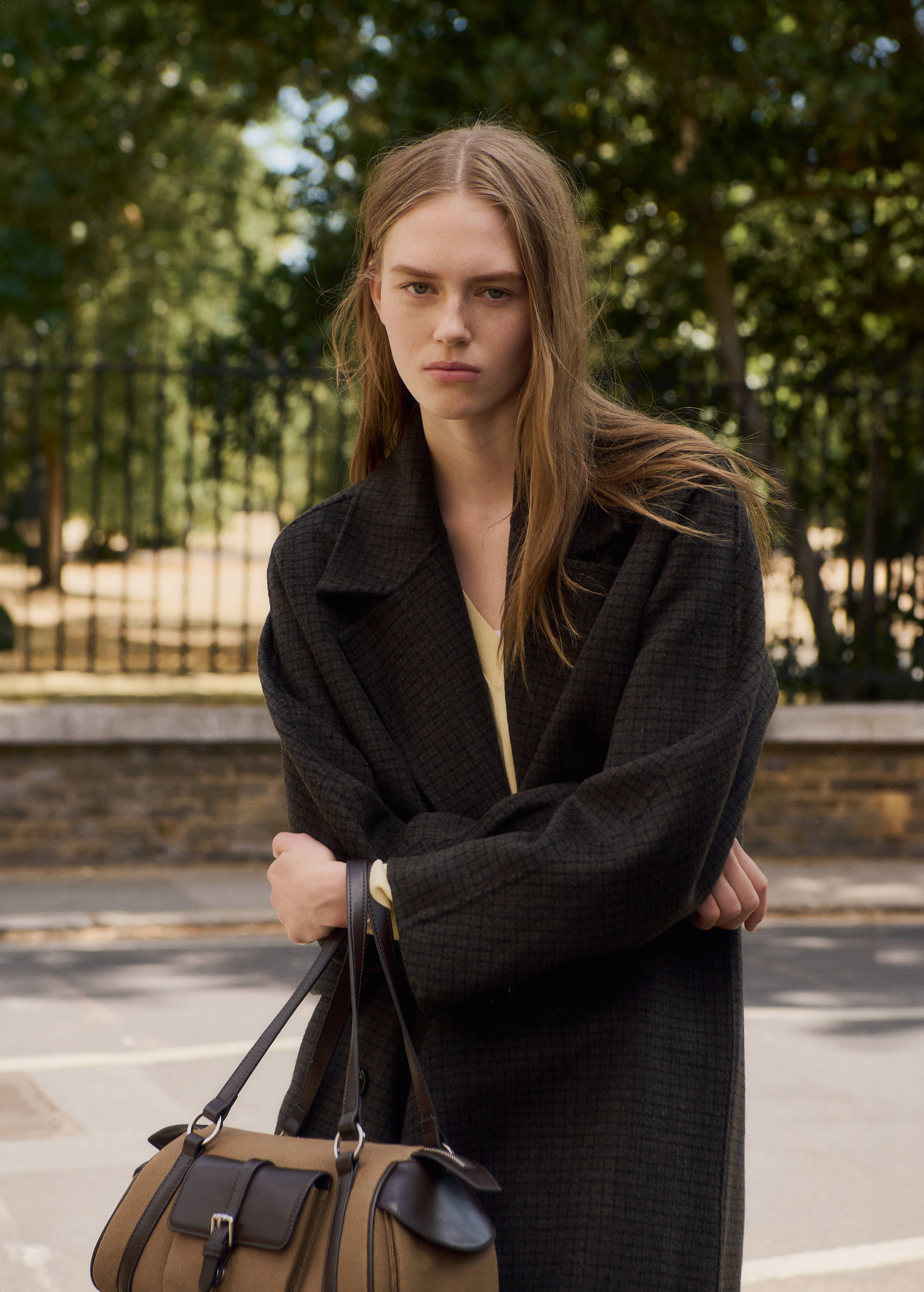 Brown canvas shoulder bag with dark leather trim, front buckle pockets, and thin straps.
