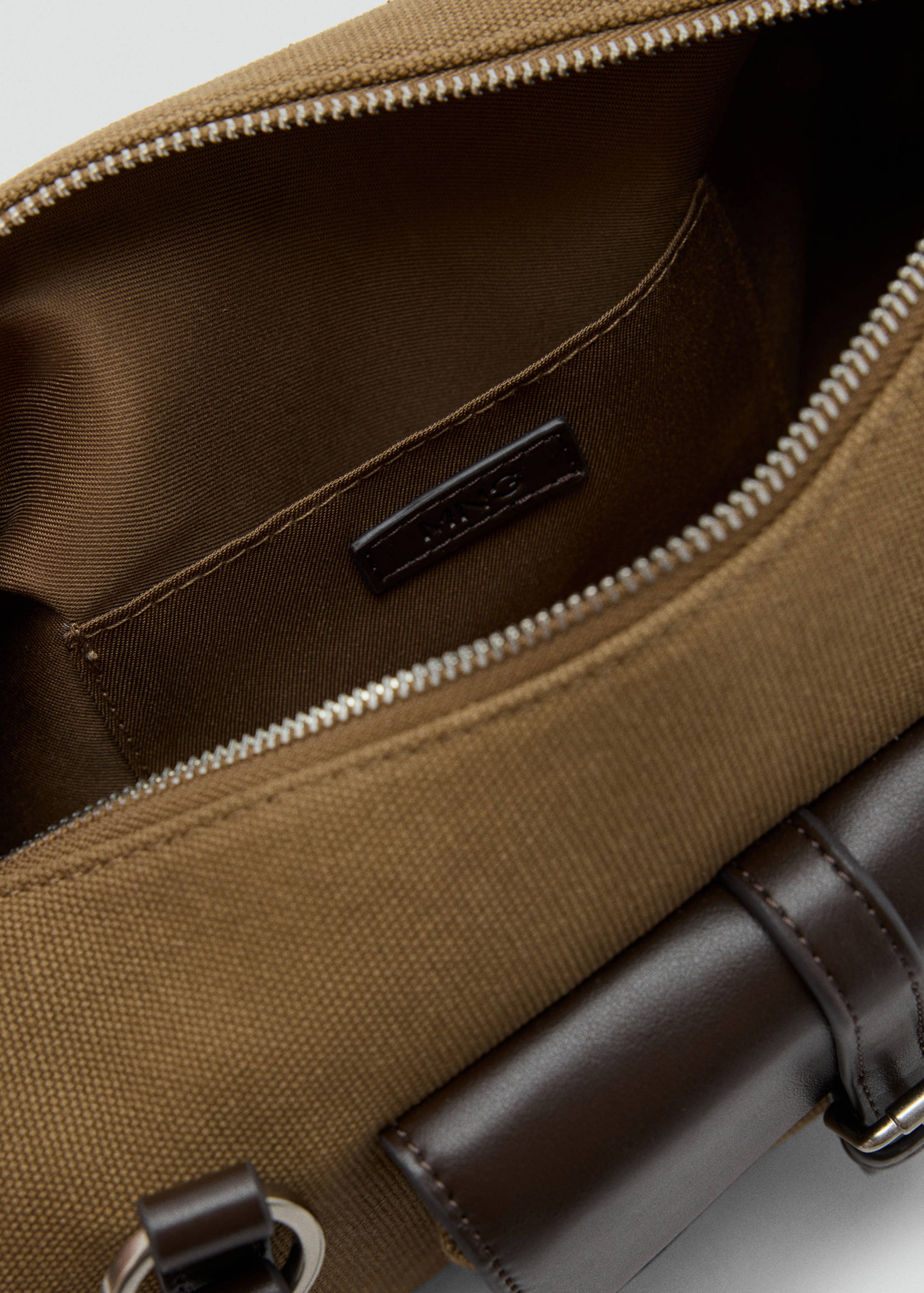 Close-up of the interior and zip detail of a brown canvas shoulder bag.