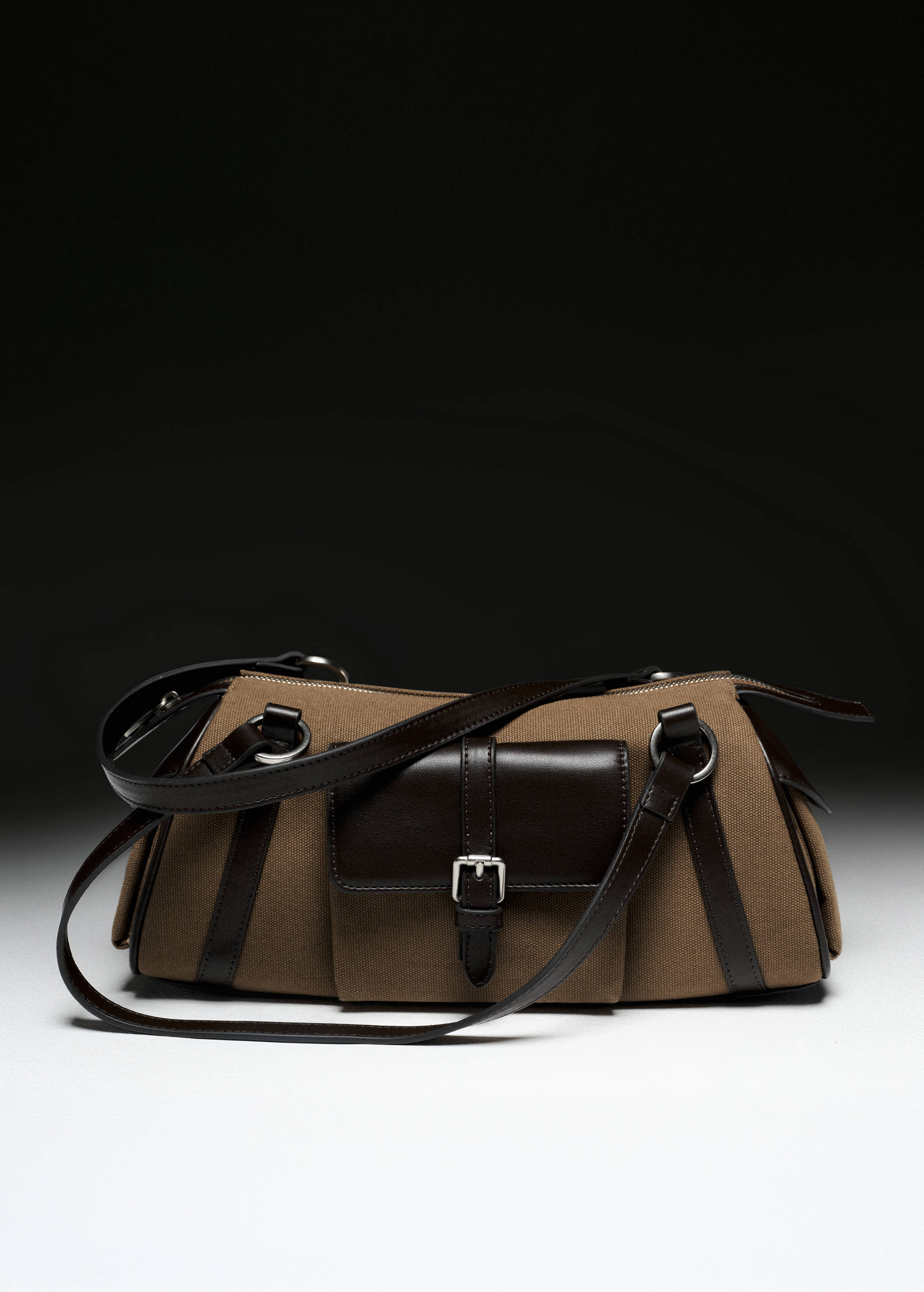 Brown canvas shoulder bag with dark brown leather trim, buckle-fastened front pocket, and silver-tone hardware.