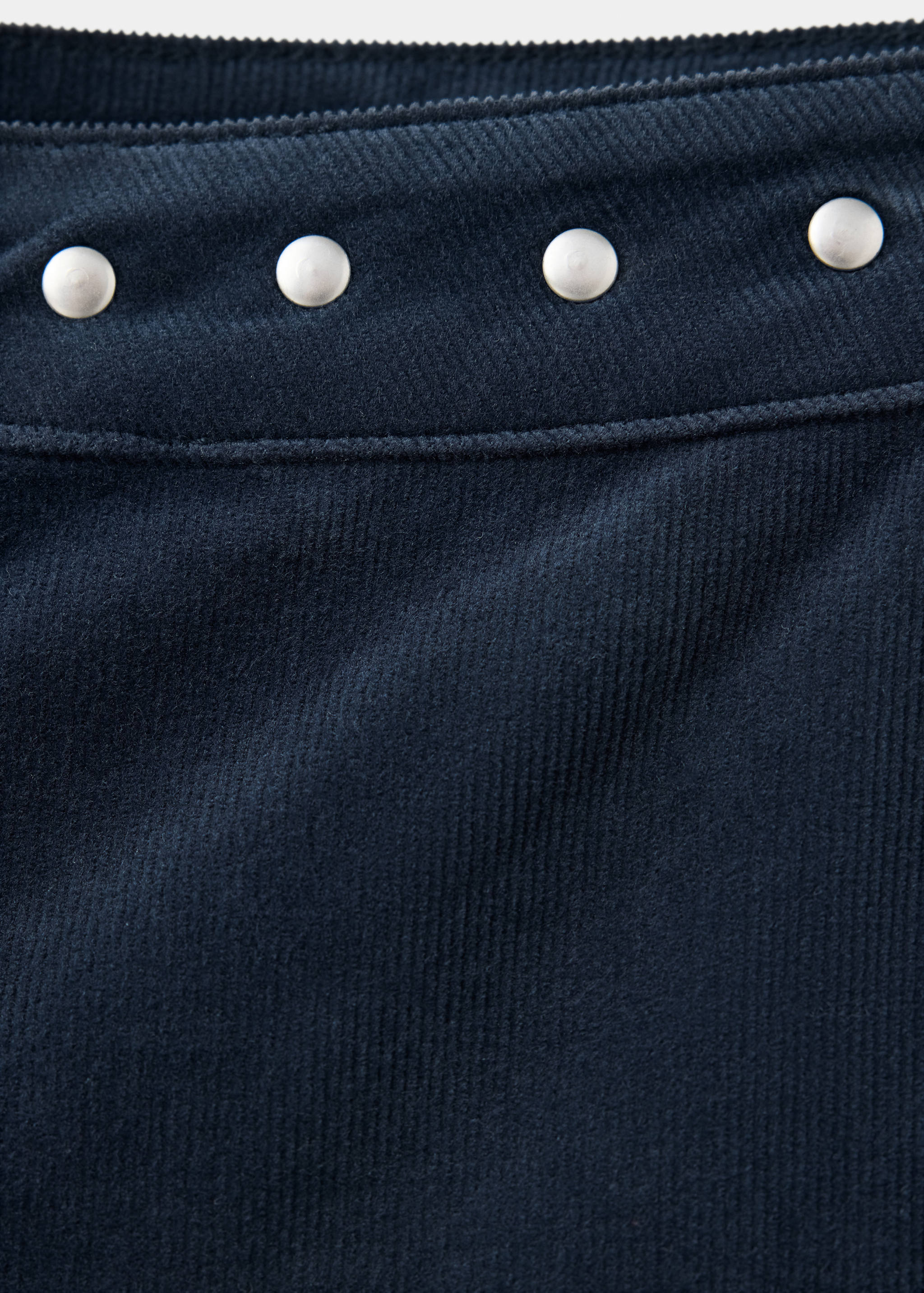 Close-up of navy blue corduroy fabric with silver studs.