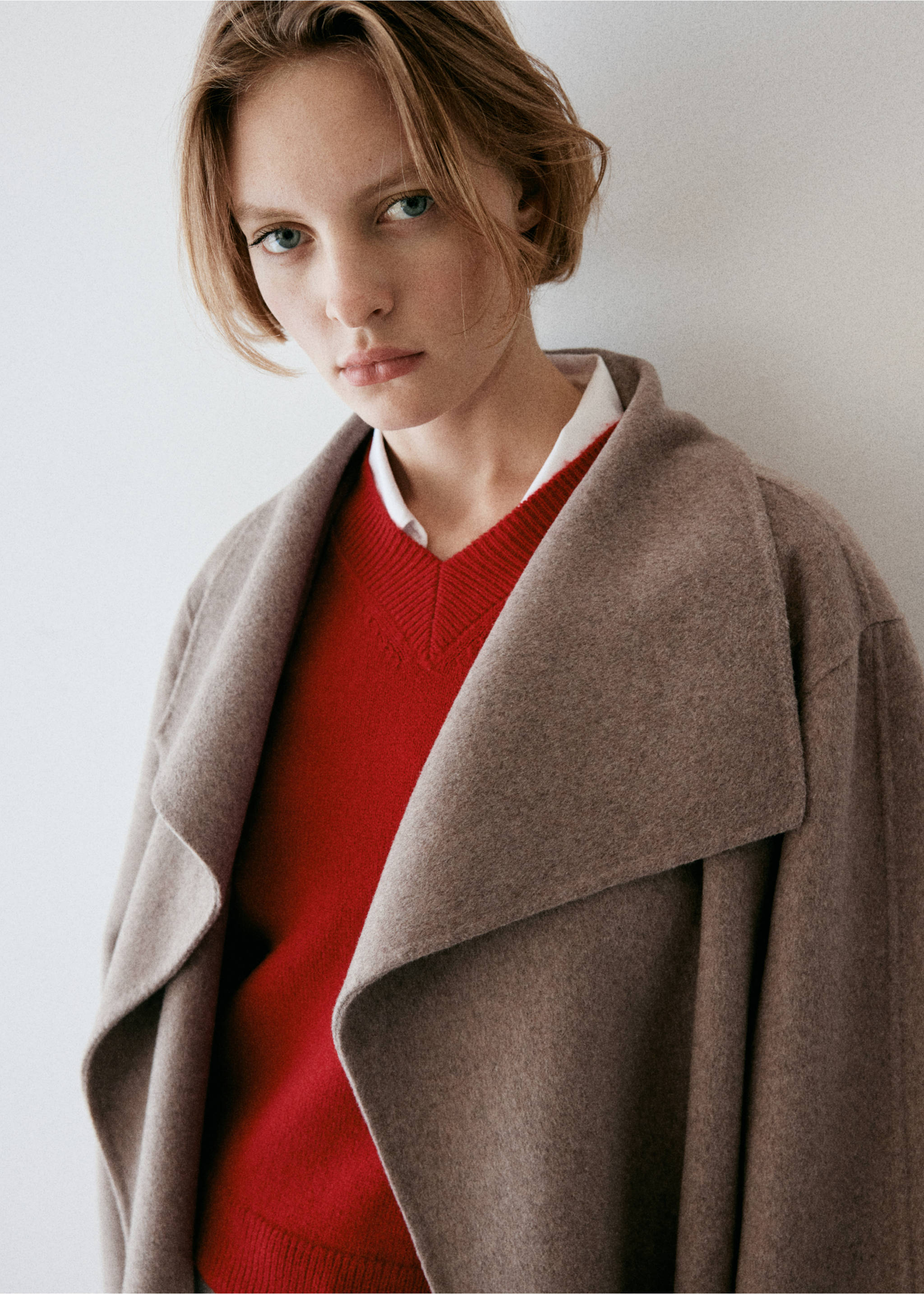 Taupe coat with wide collar, worn over a red V-neck sweater, Medium Brown. Ref: 37036728-01.