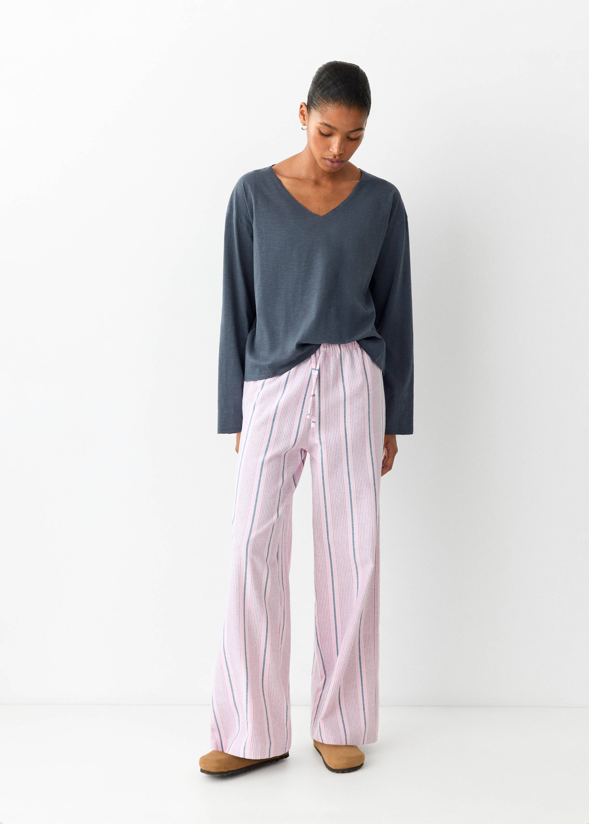 Grey V-neck pyjama top worn with pink and dark striped trousers.
