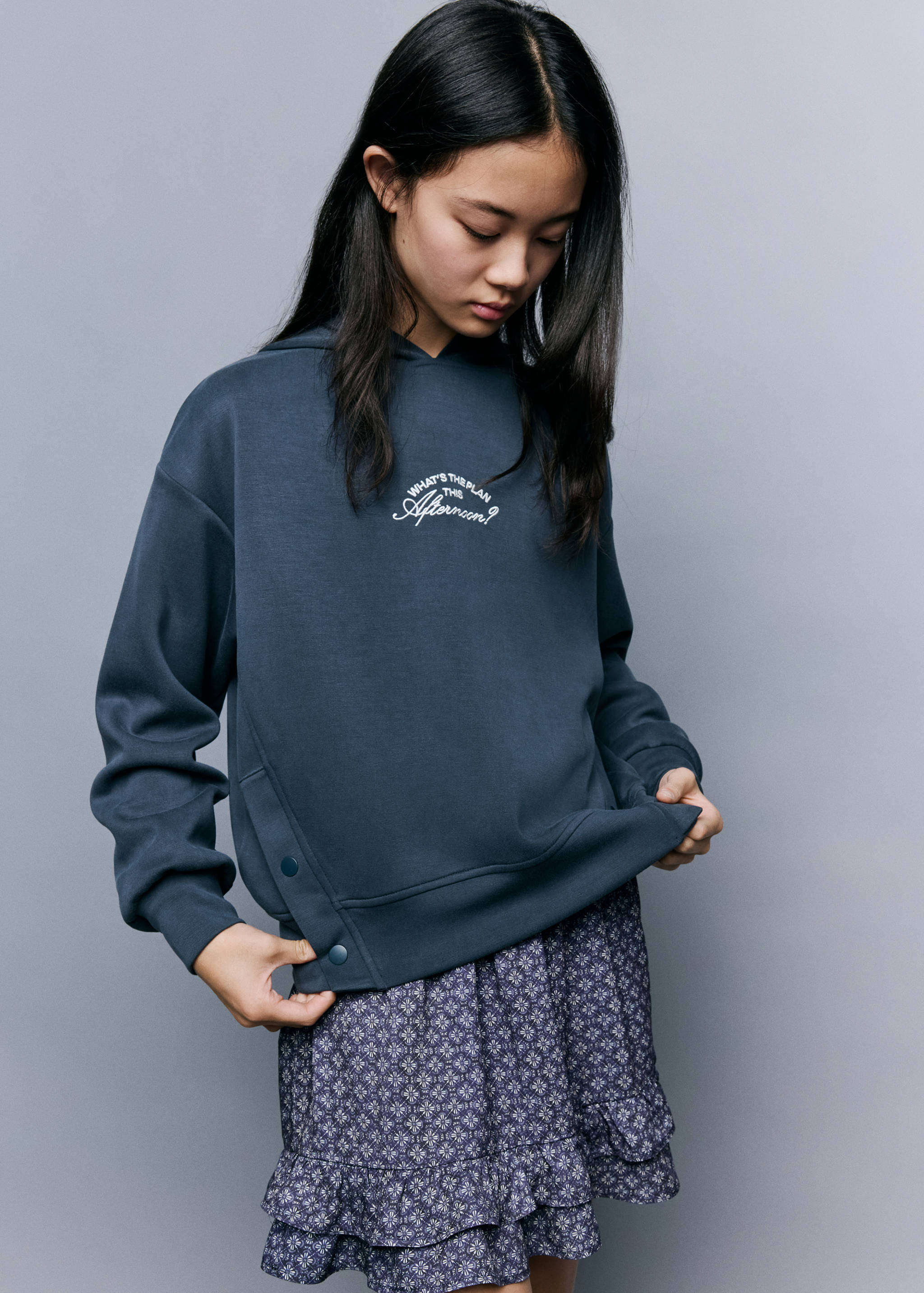 Dark blue kids hooded sweatshirt with chest text and snap button side detail.