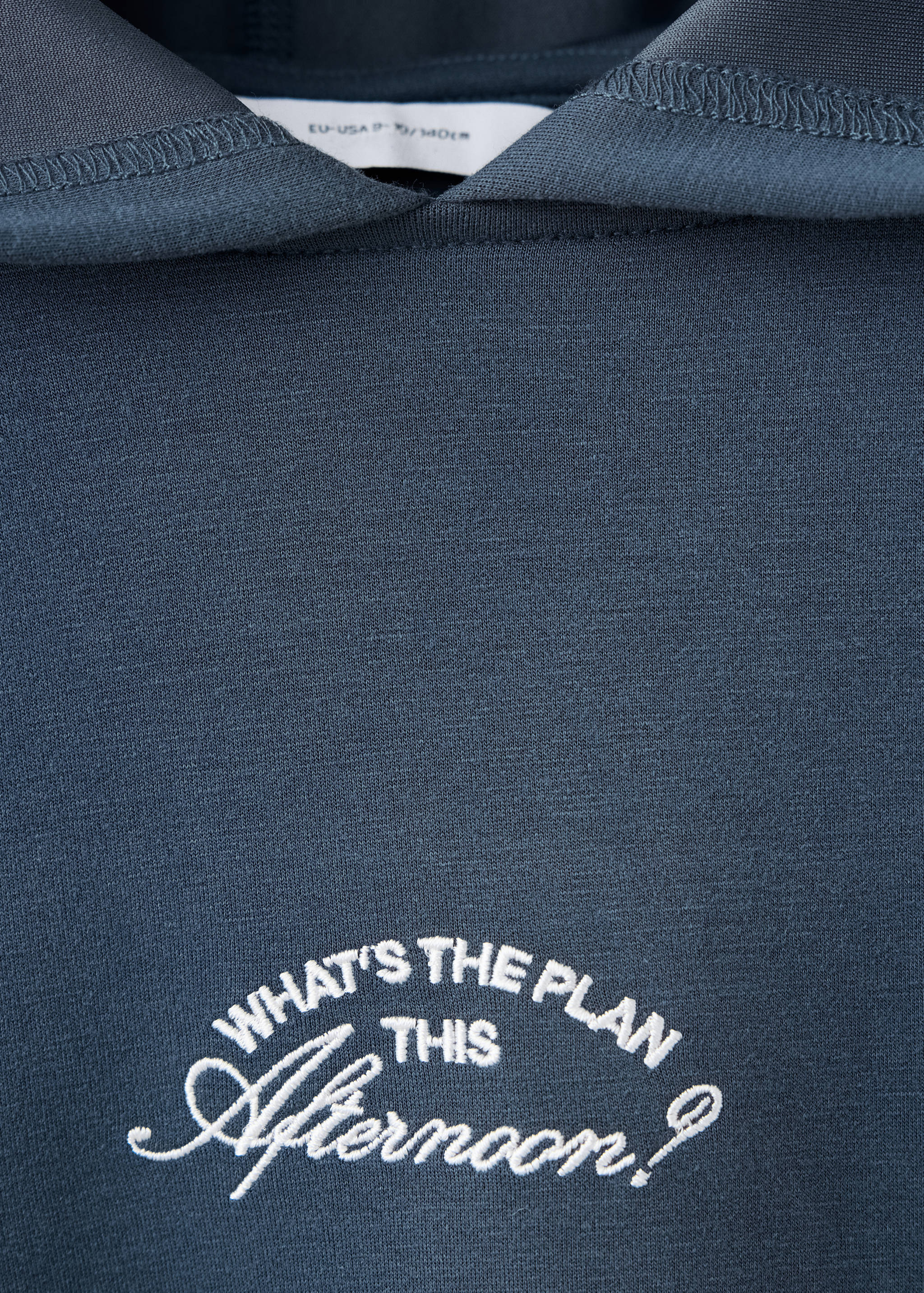 Dark blue children's hoodie detail with white chest embroidery.