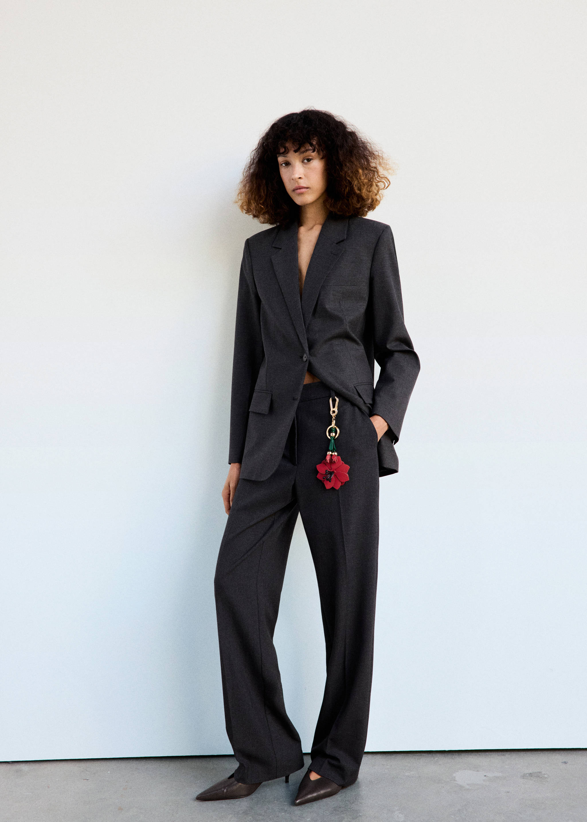 Red flower keyring attached to the waistband of a dark grey suit