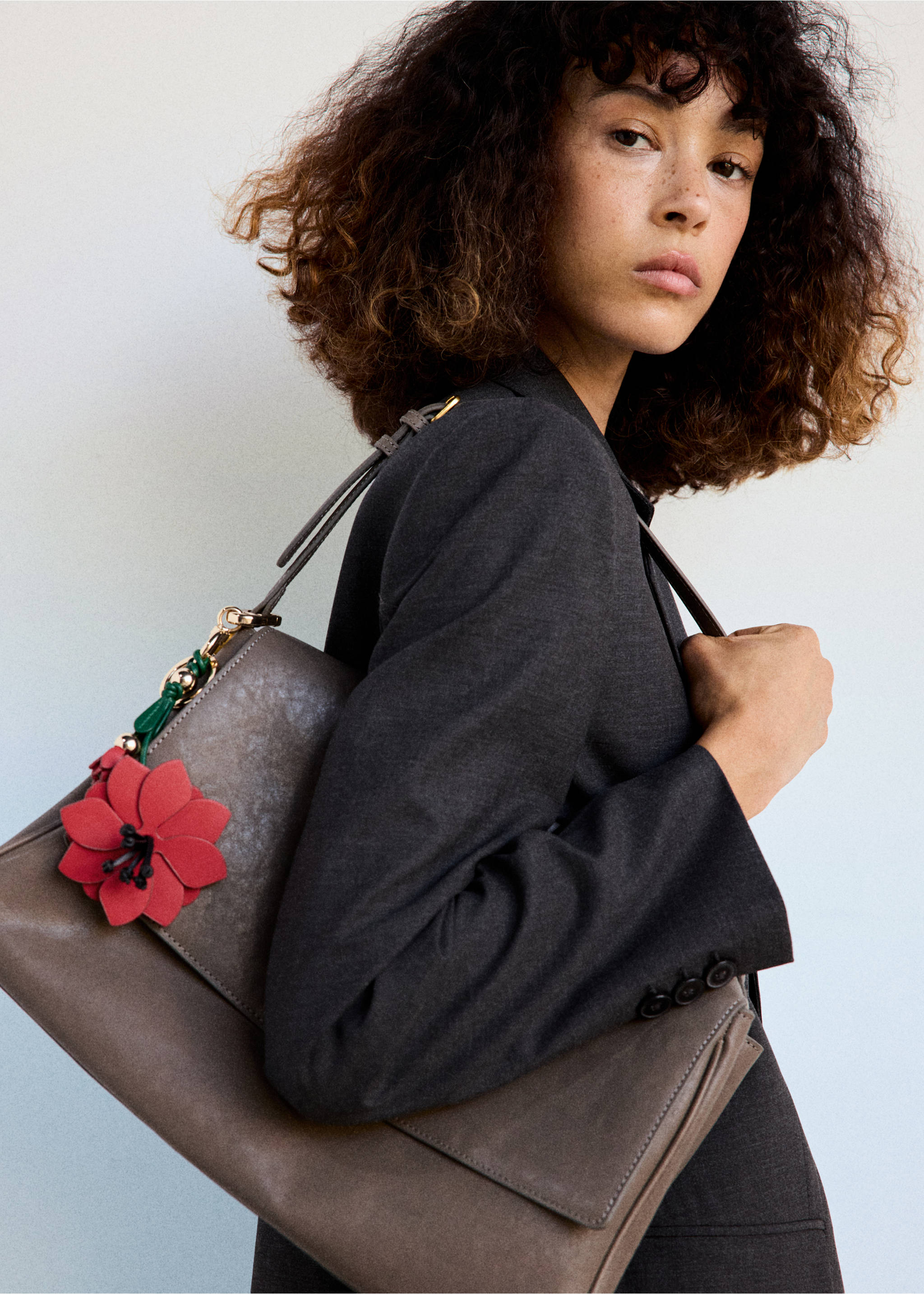 Red and green floral keychain attached to a grey shoulder bag., Red. Ref: 37036749-00.