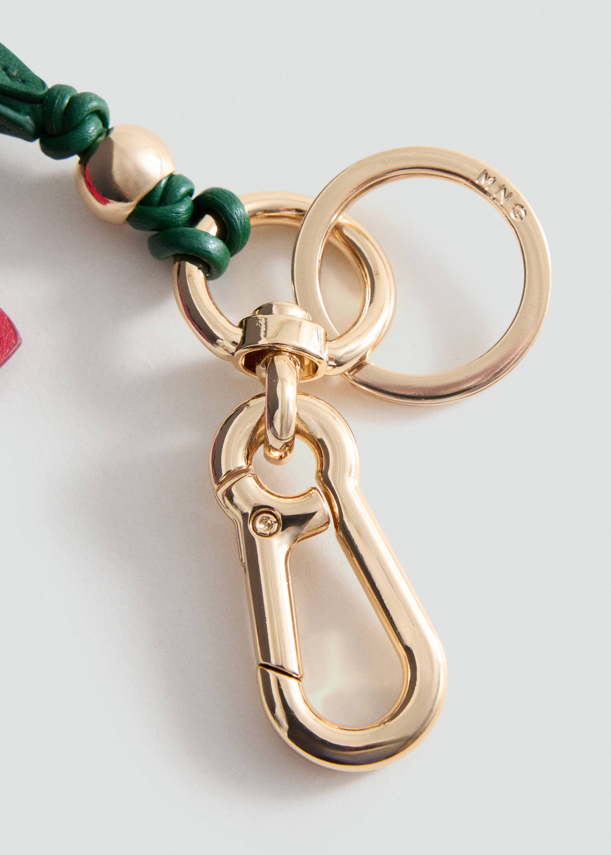 Close-up of a green leather keychain with gold-tone hardware.