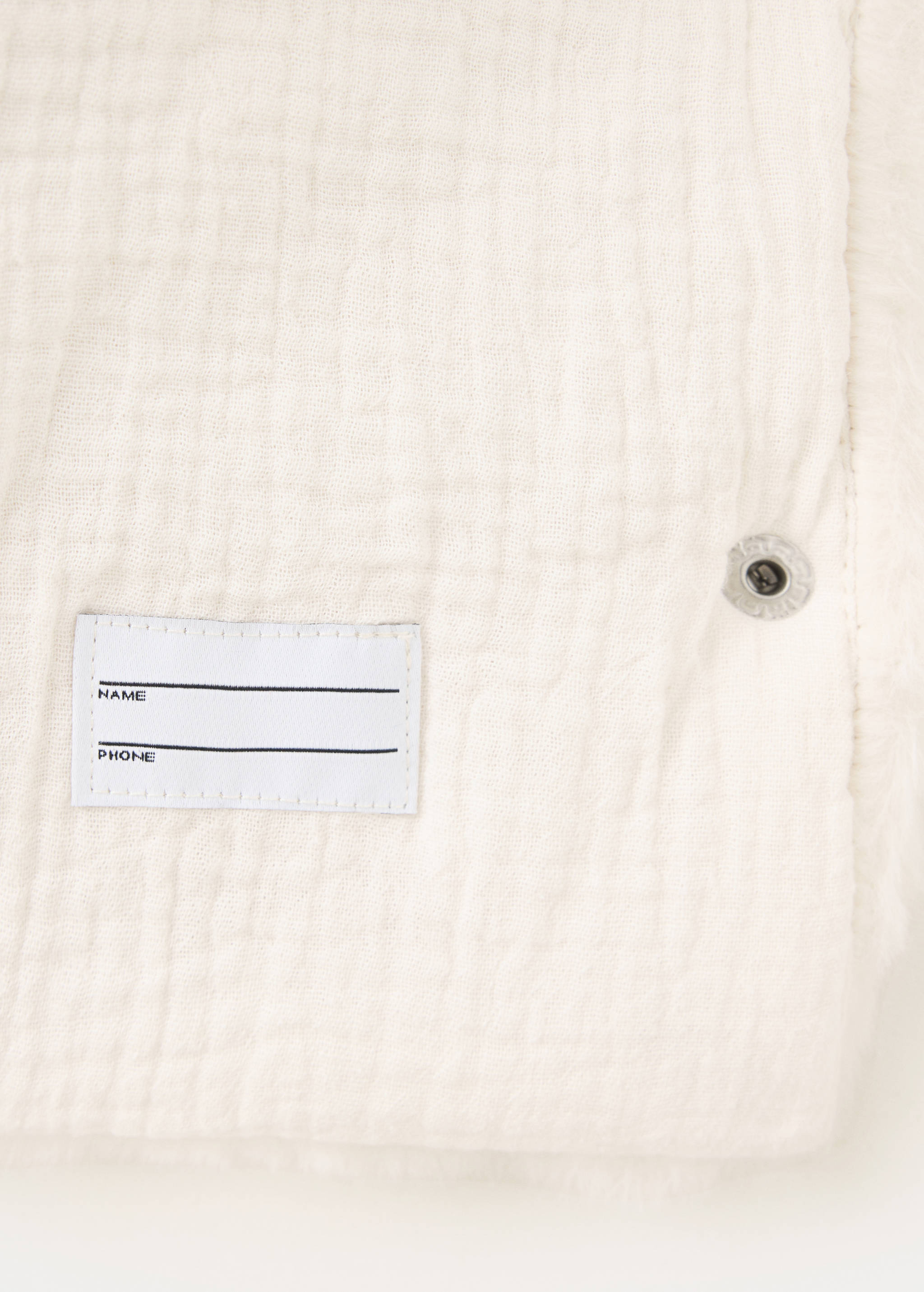 Close-up of a white coat showing a name tag detail.