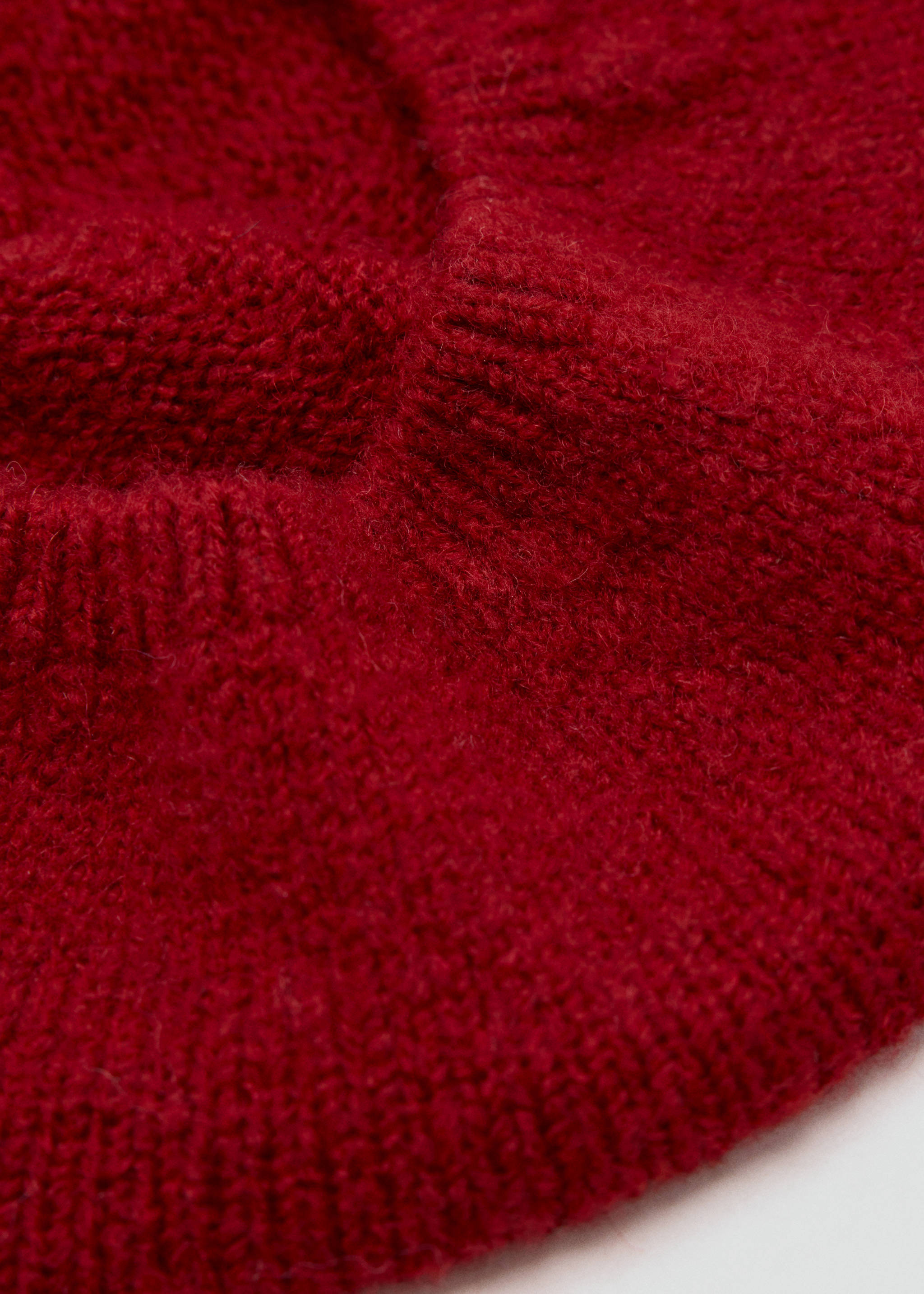 Close-up of a red knit beanie showing its fuzzy texture and ribbed cuff.